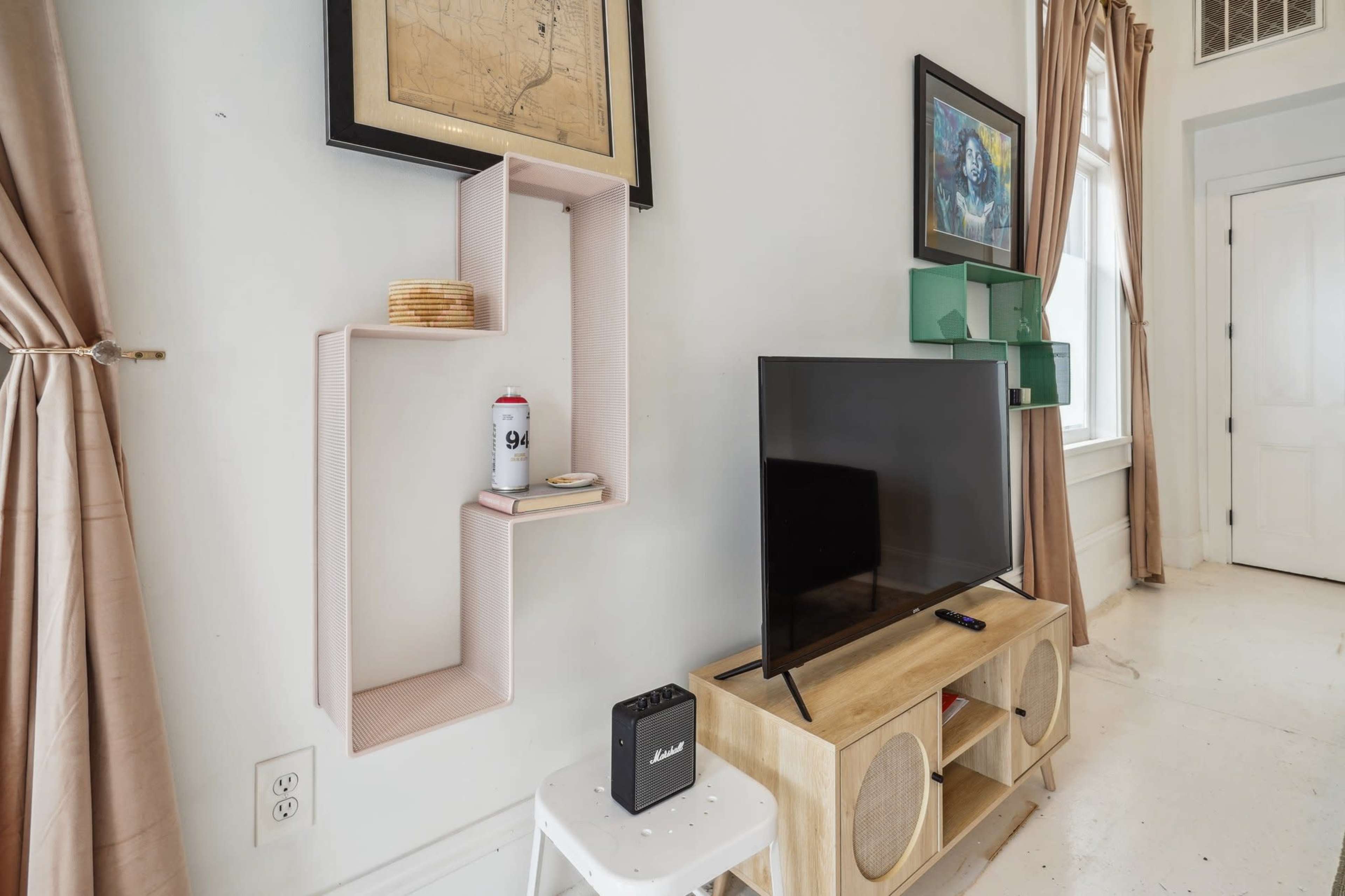 A modern living room with a wall-mounted shelf, a television, and decorative elements including a framed map and artwork.