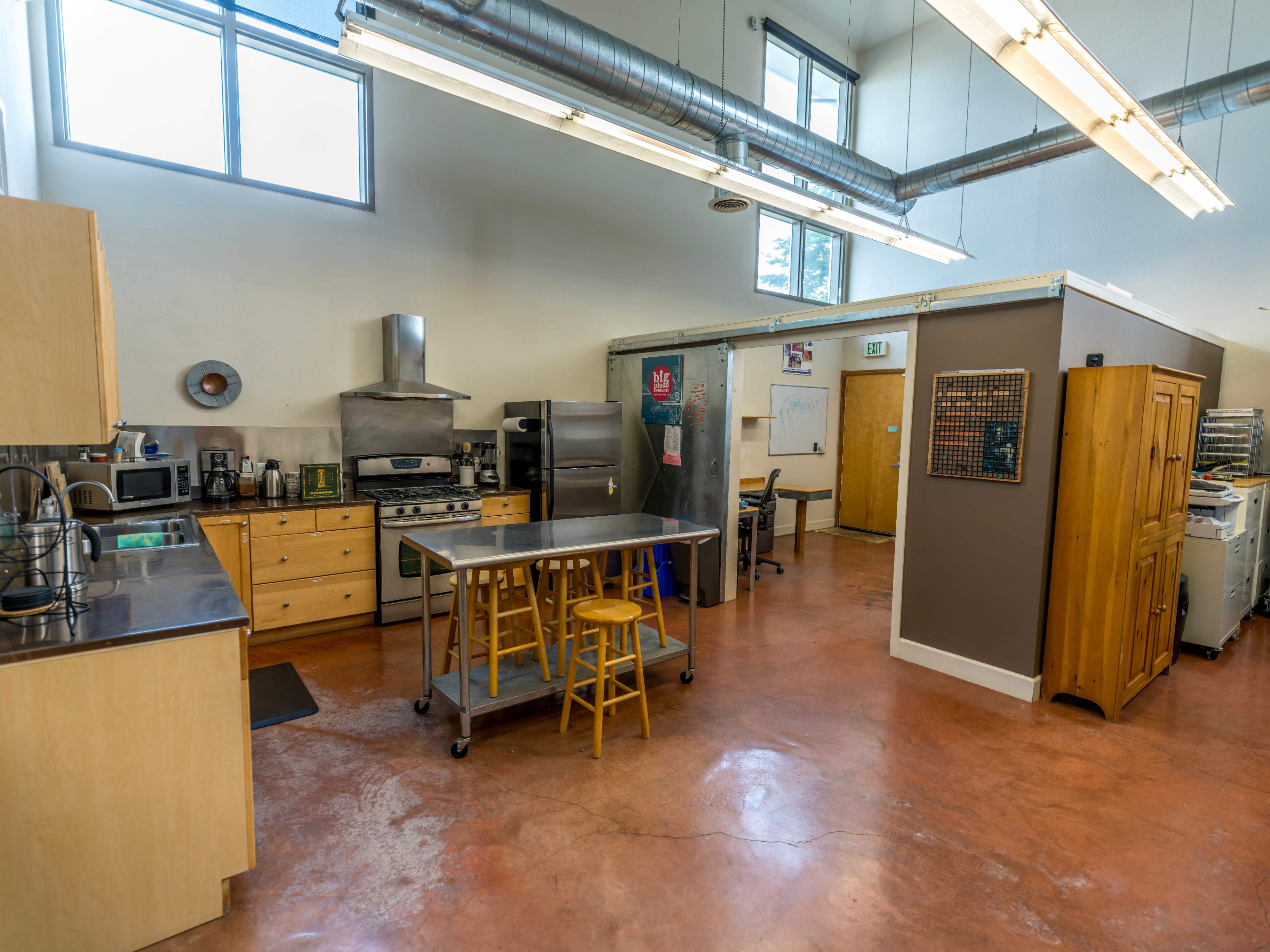 A spacious kitchen with stainless steel appliances, wooden cabinetry, and a central island with stools.