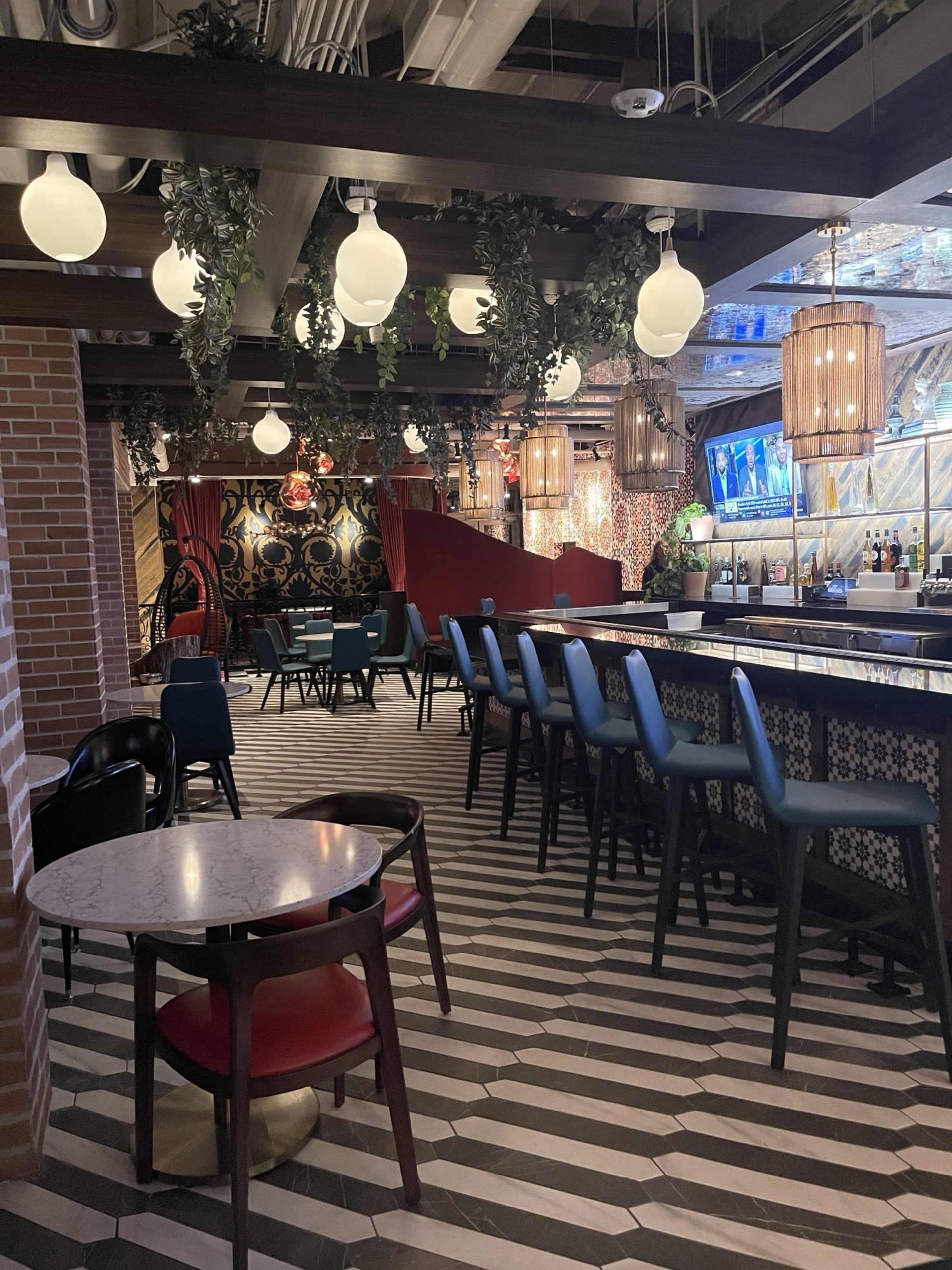 The image shows a stylish bar area with a patterned floor, a long bar counter, and various types of hanging lights.