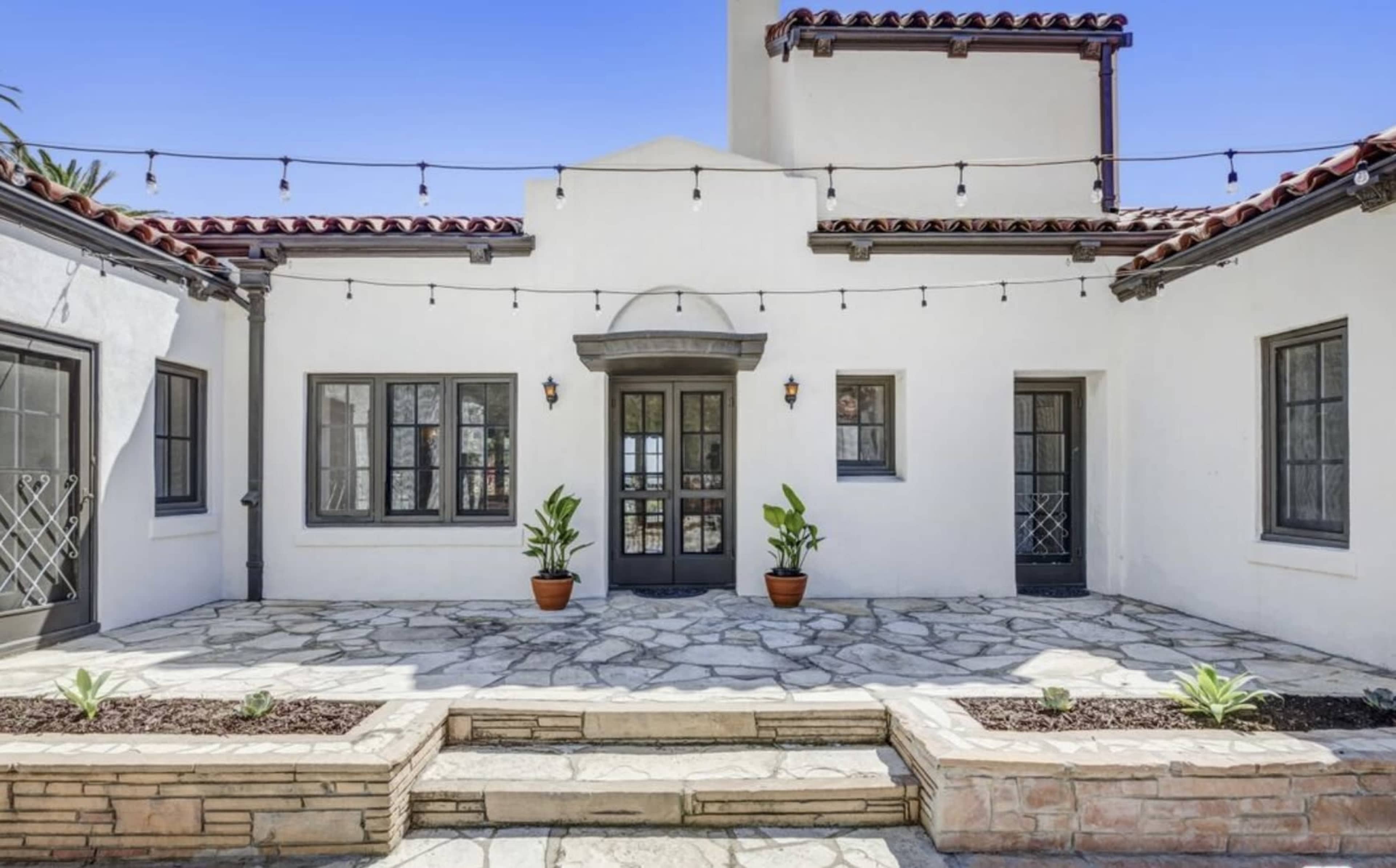 A landscaped courtyard area with stone flooring, potted plants, and string lights illuminating the space.