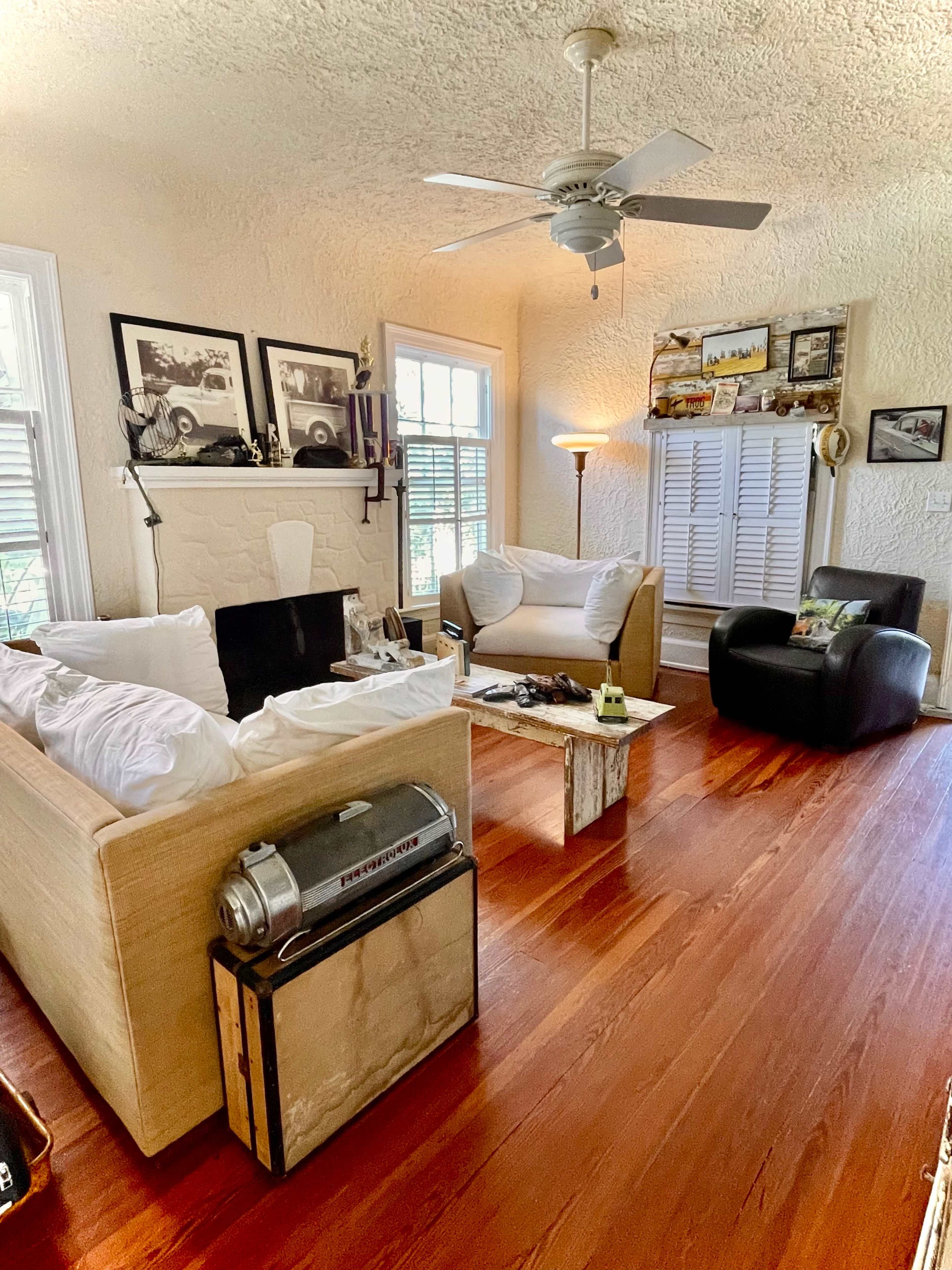 The living room features two couches, a coffee table made from wood, and various framed photographs on the walls.