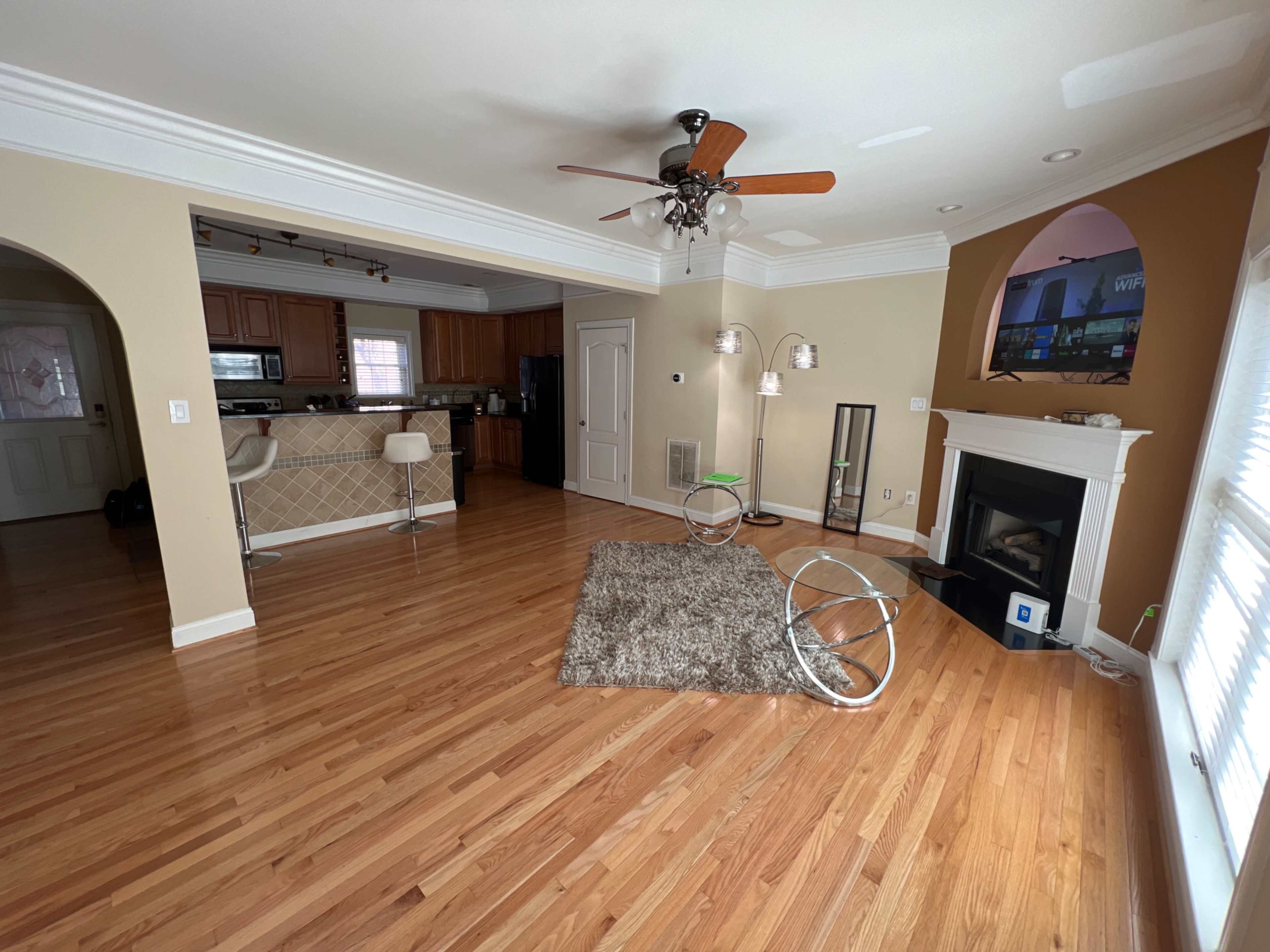 A spacious living room with hardwood floors, a fireplace, and a bar area in the adjacent kitchen.
