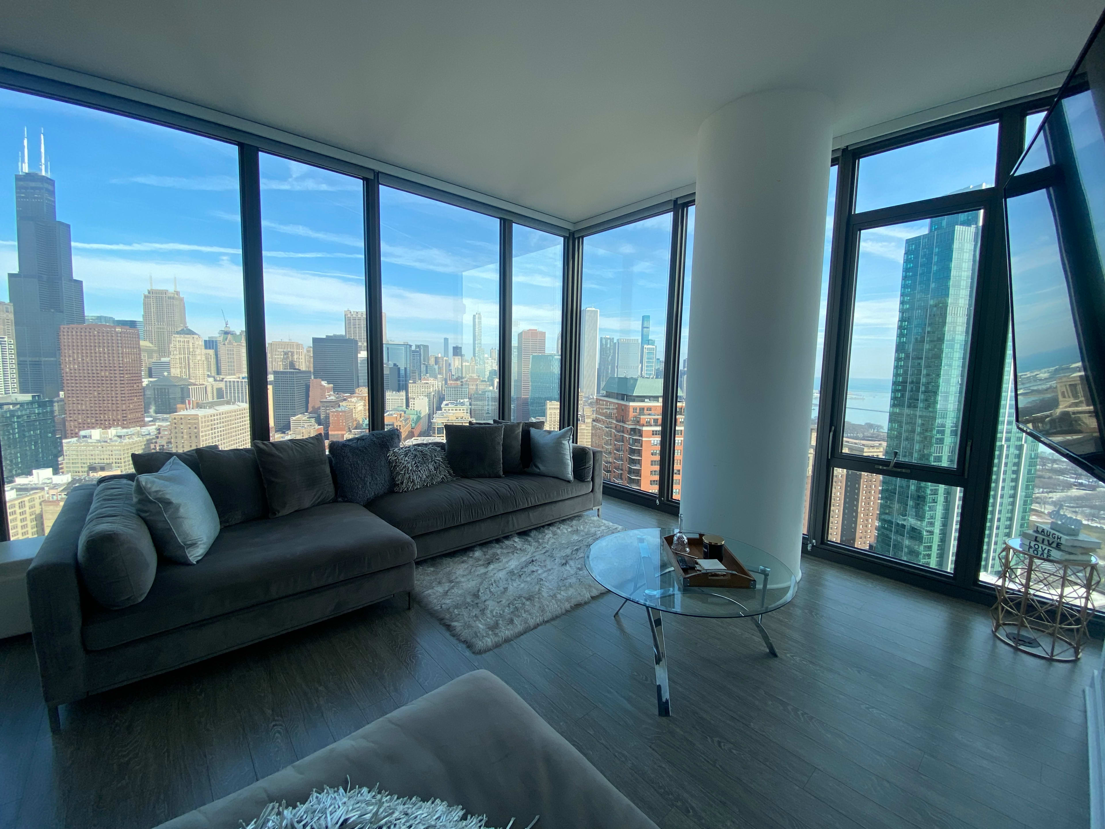A modern living room with large windows offering a view of the Chicago skyline and Lake Michigan.