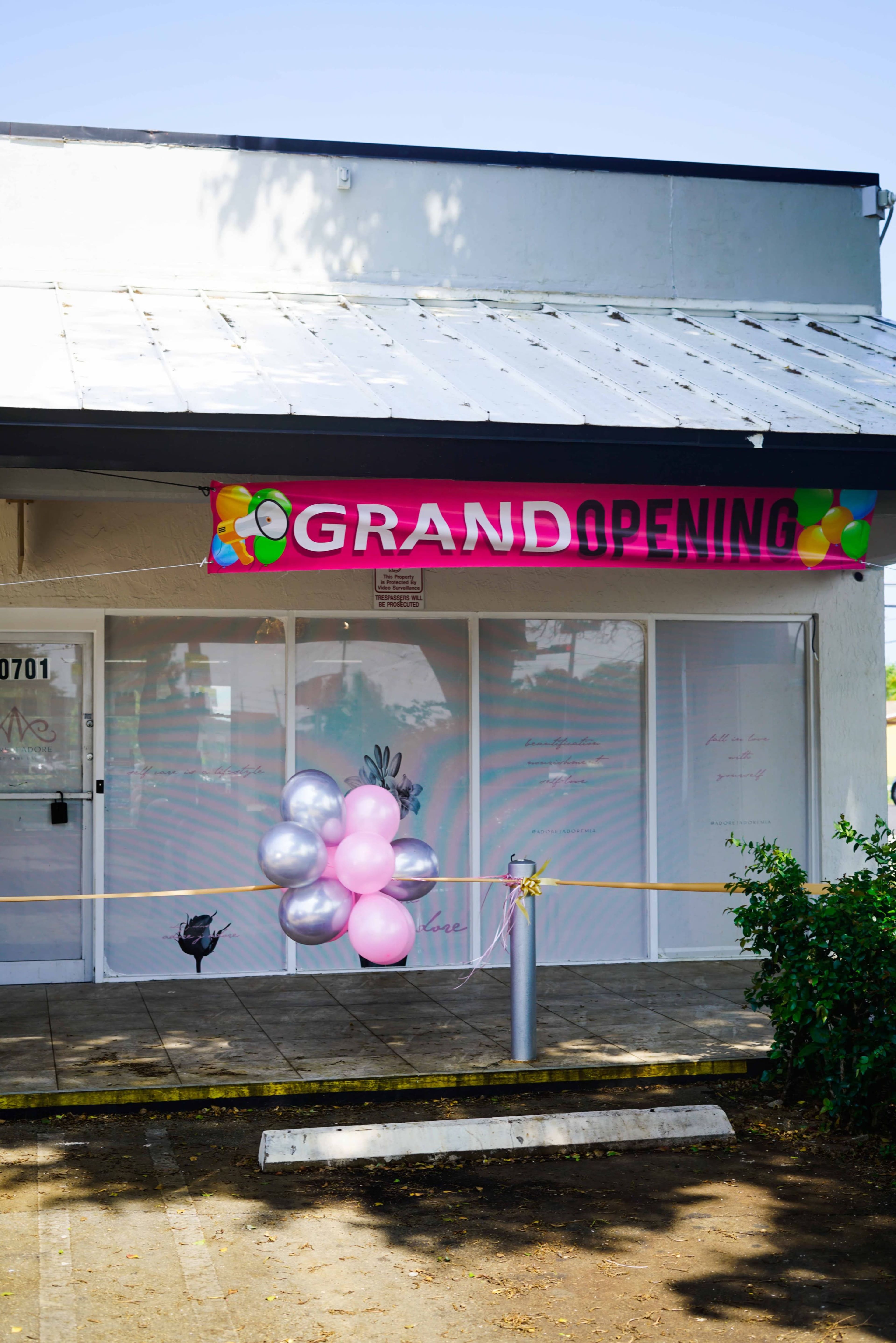 A storefront features a "GRAND OPENING" banner and a cluster of balloons in front of the entrance.
