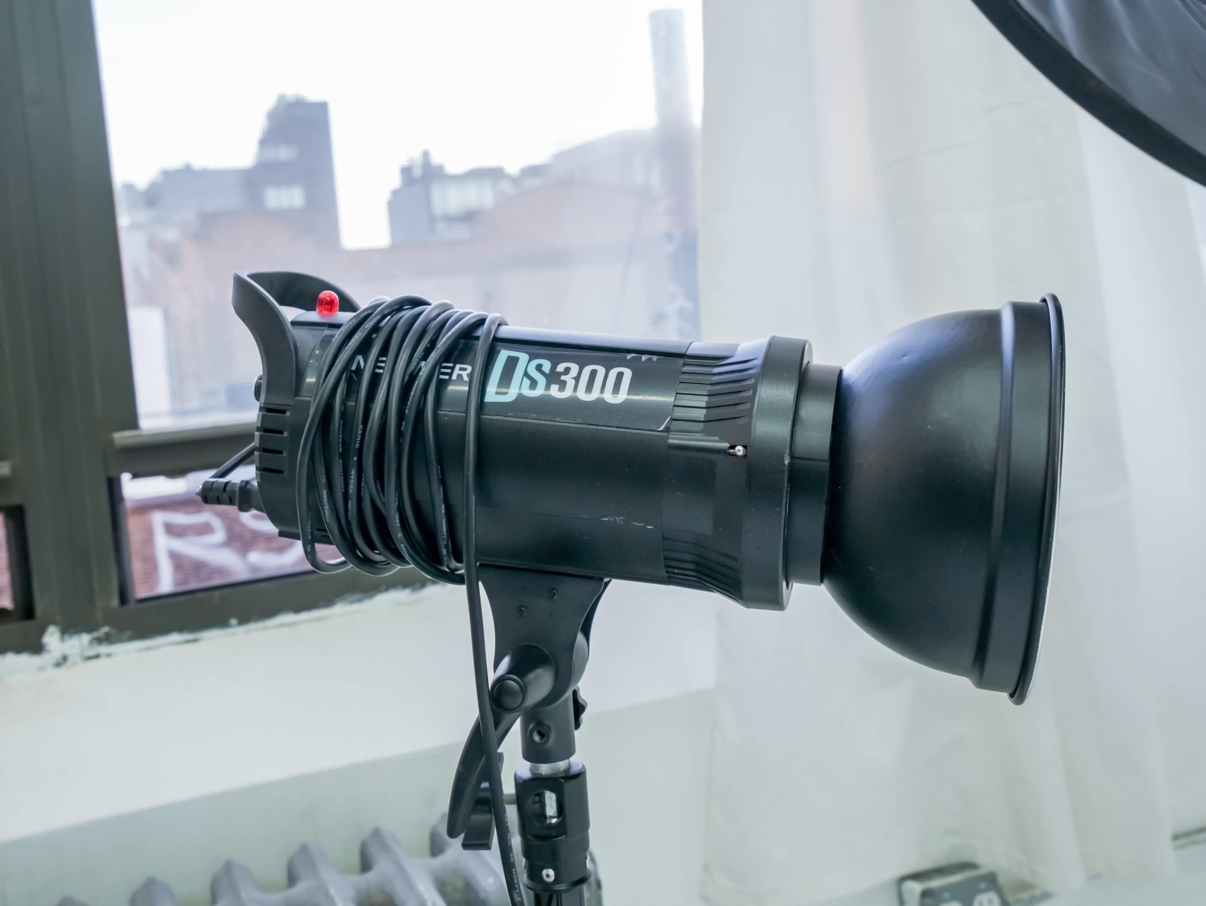 A photography studio lighting fixture is mounted on a stand near a window.