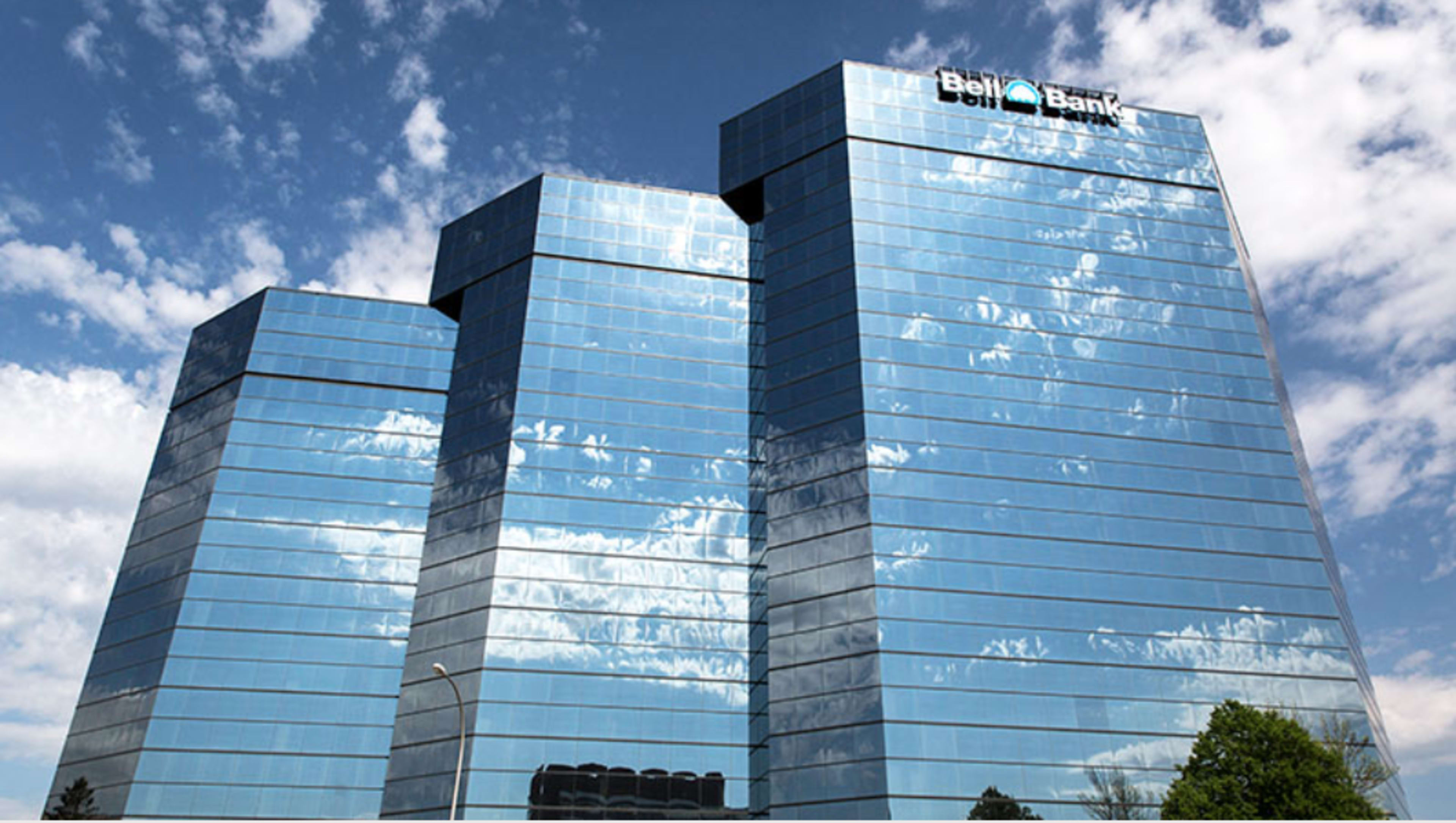 A large, modern bank building with a reflective glass exterior under a partly cloudy sky.