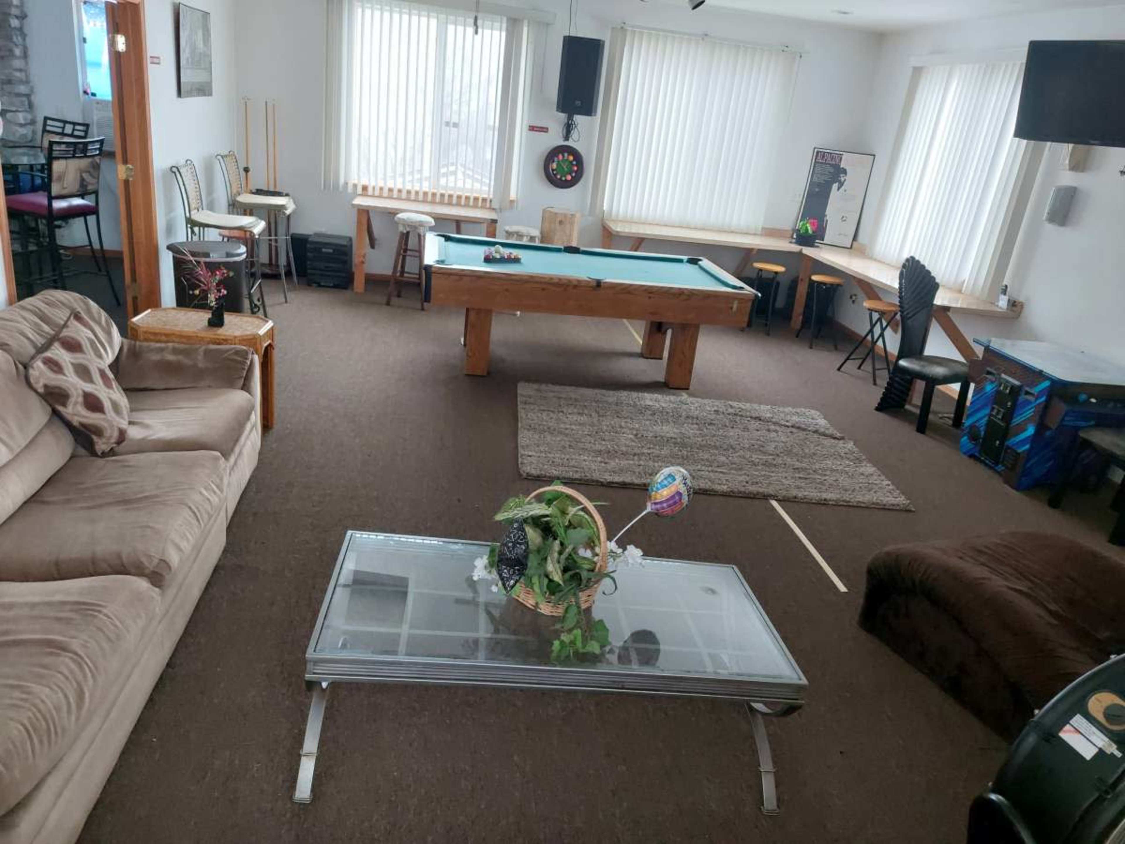 A spacious recreational room features a pool table, a seating area with a couch, and various game and activity setups.