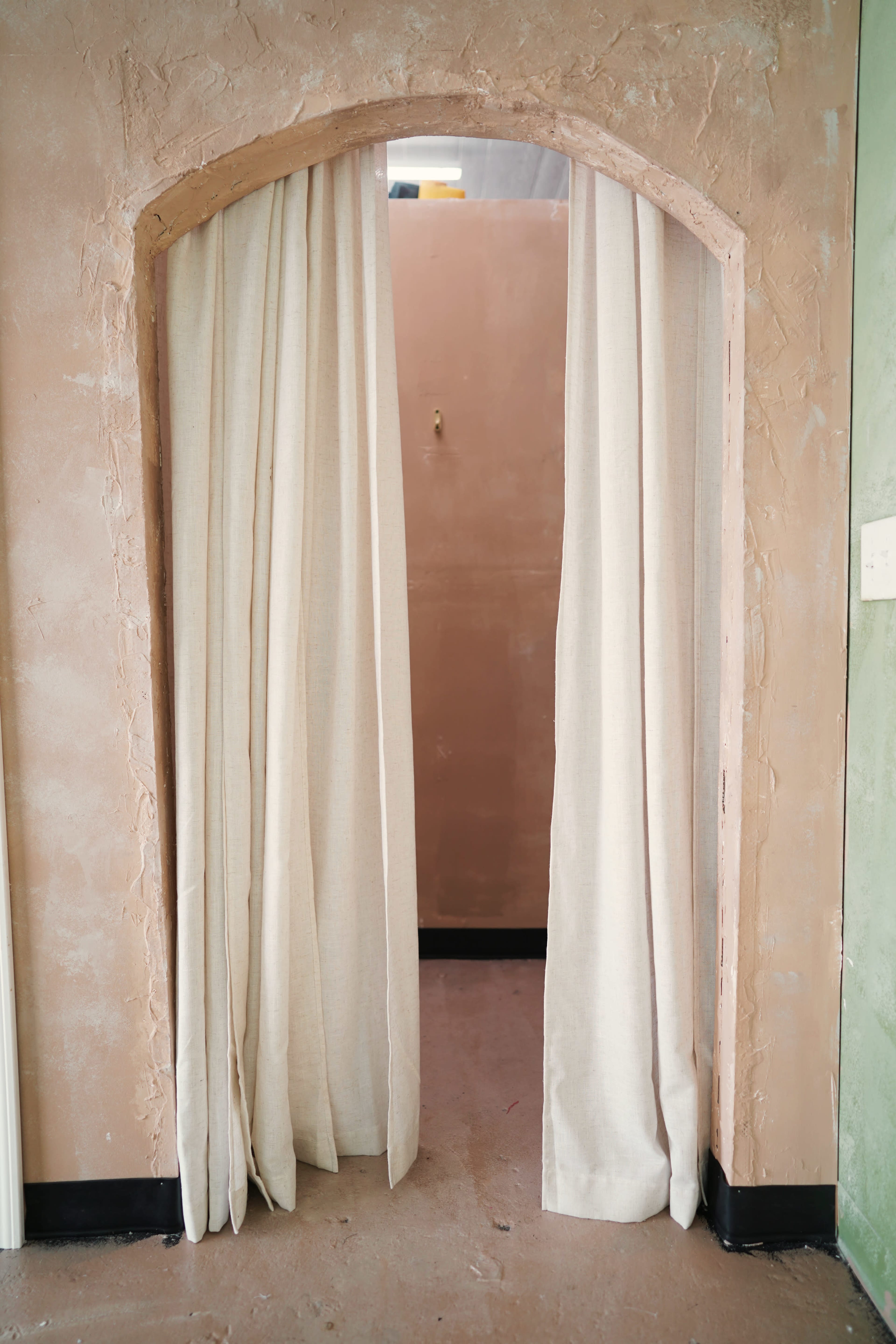 A fabric curtain hangs in an arched doorway, leading into a room with a plain wall.