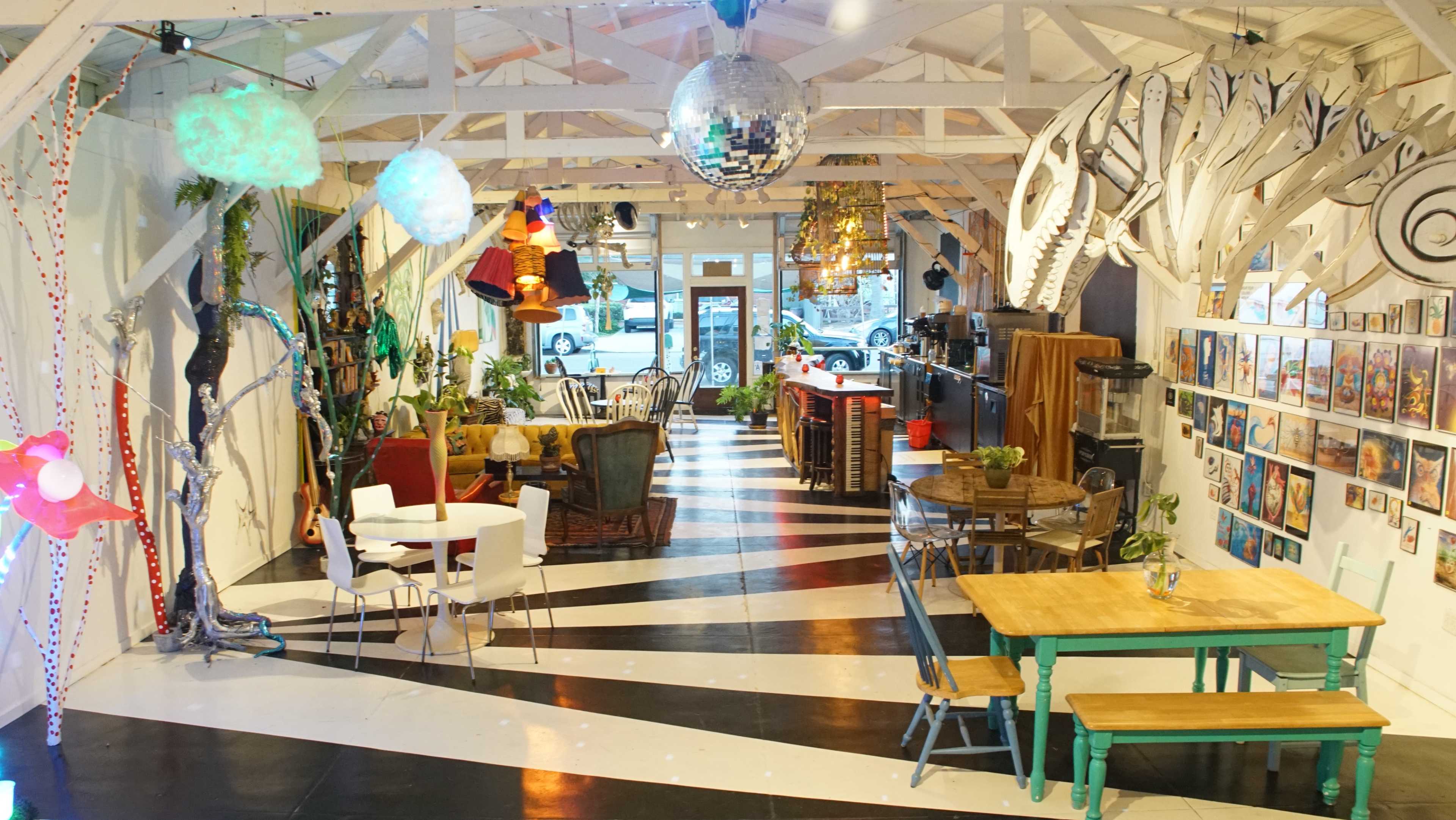The image shows a vibrant café interior with black and white striped flooring, colorful decor, and various seating arrangements.