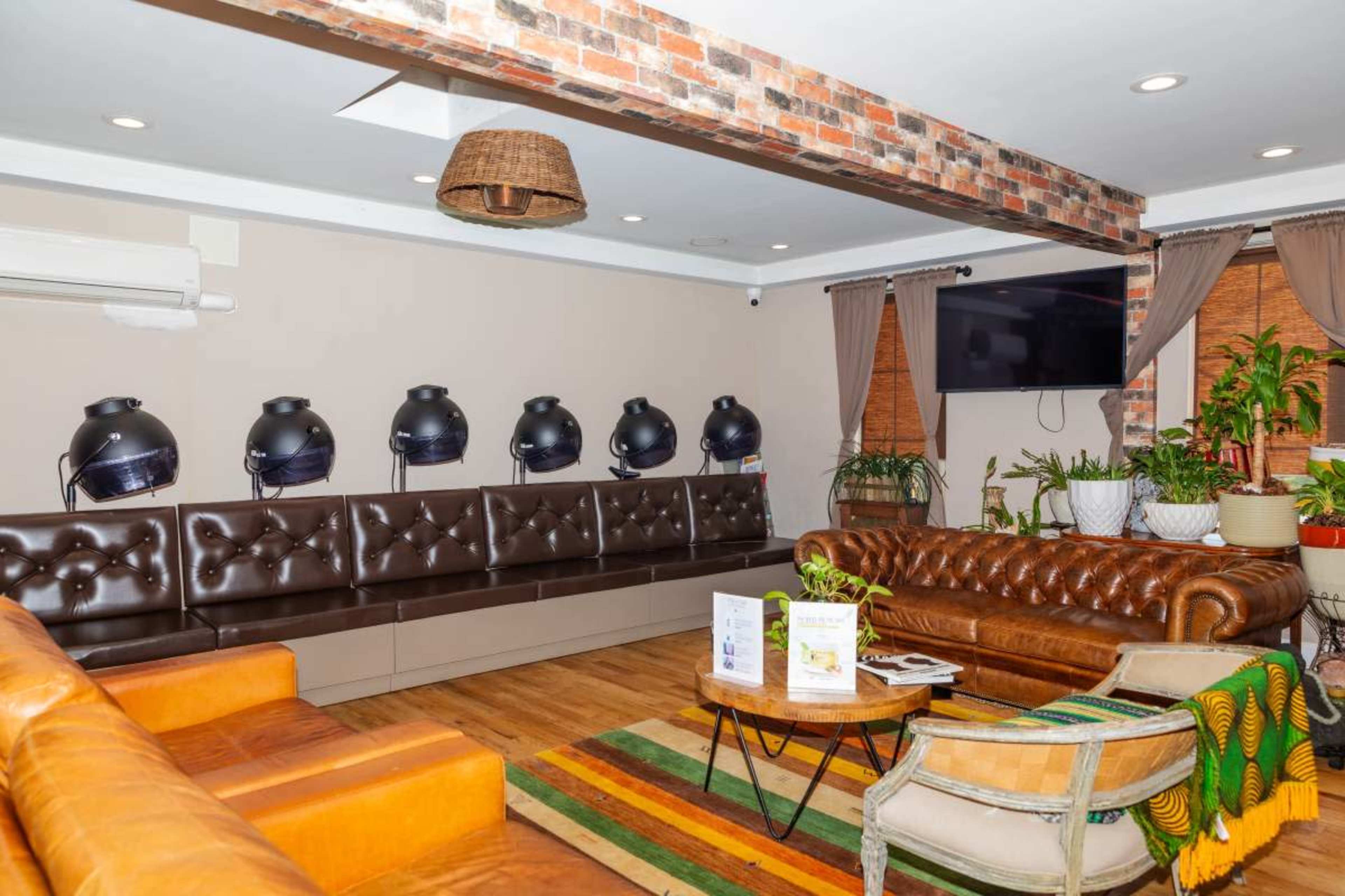 The scene depicts a modern lounge area with leather seating, a coffee table, and stylish lighting fixtures lined against a brick wall.