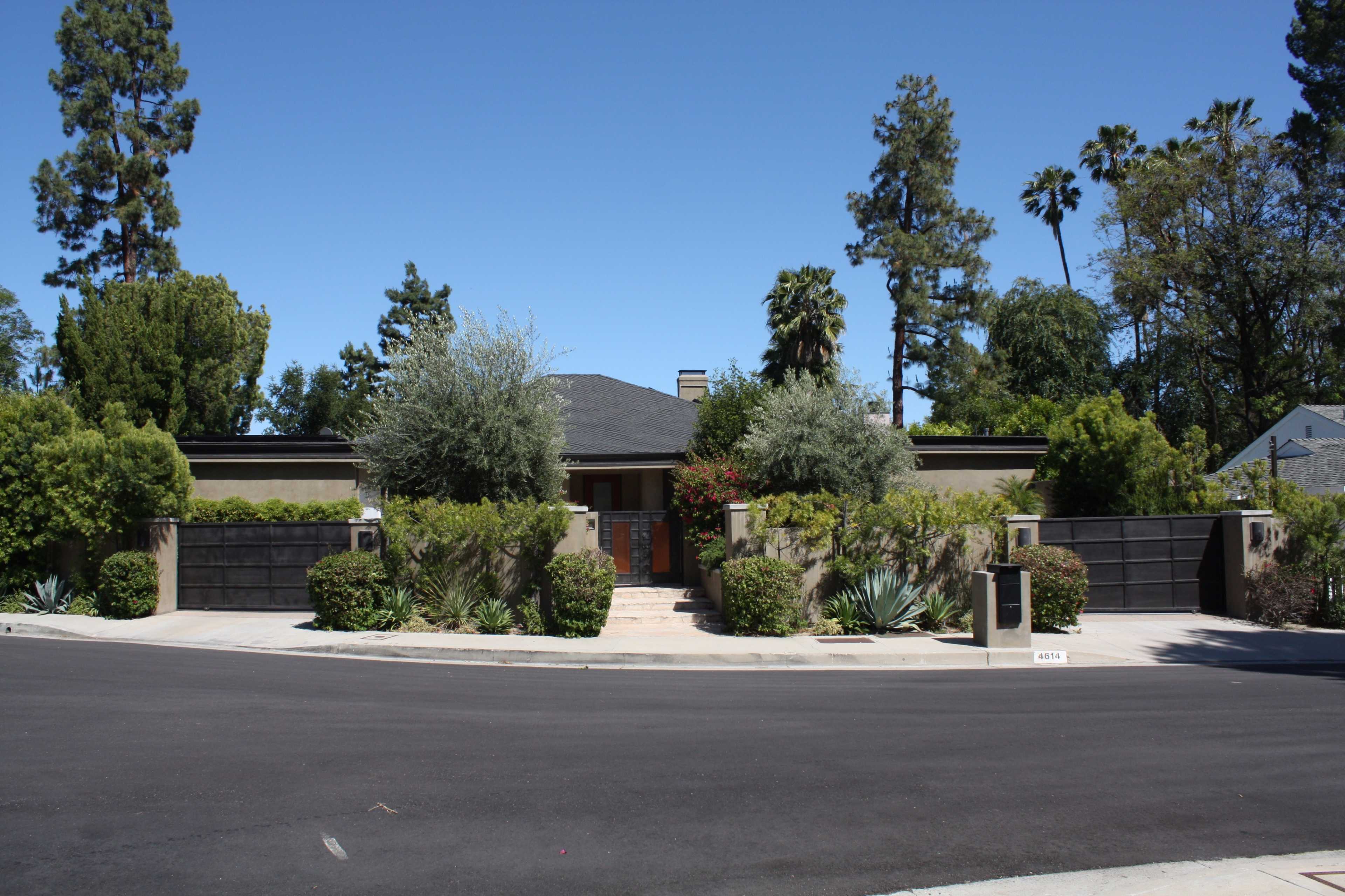 A modern house with a landscaped front yard is situated at the corner of a quiet street.