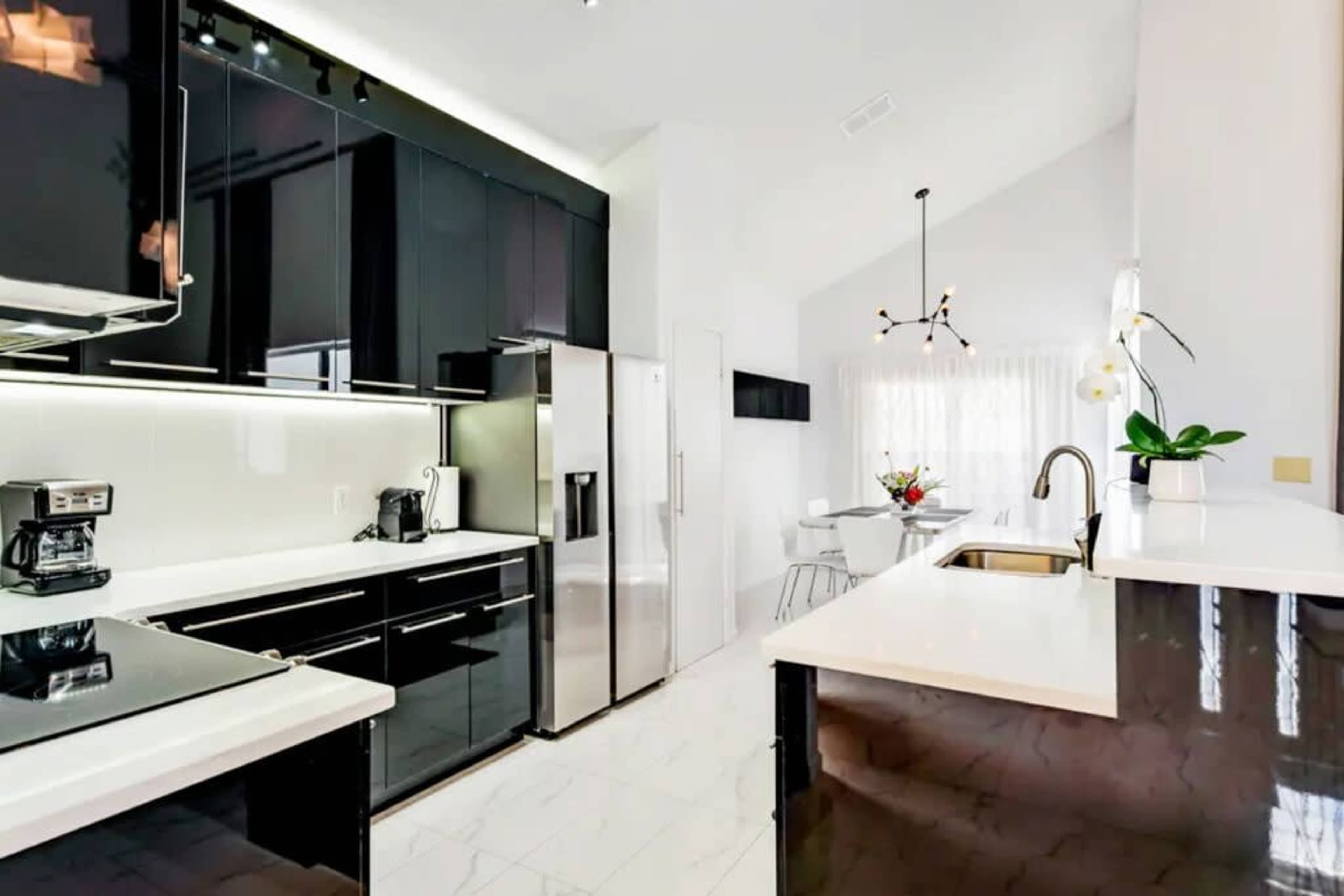 A modern kitchen featuring black cabinetry, stainless steel appliances, and a white marble countertop.