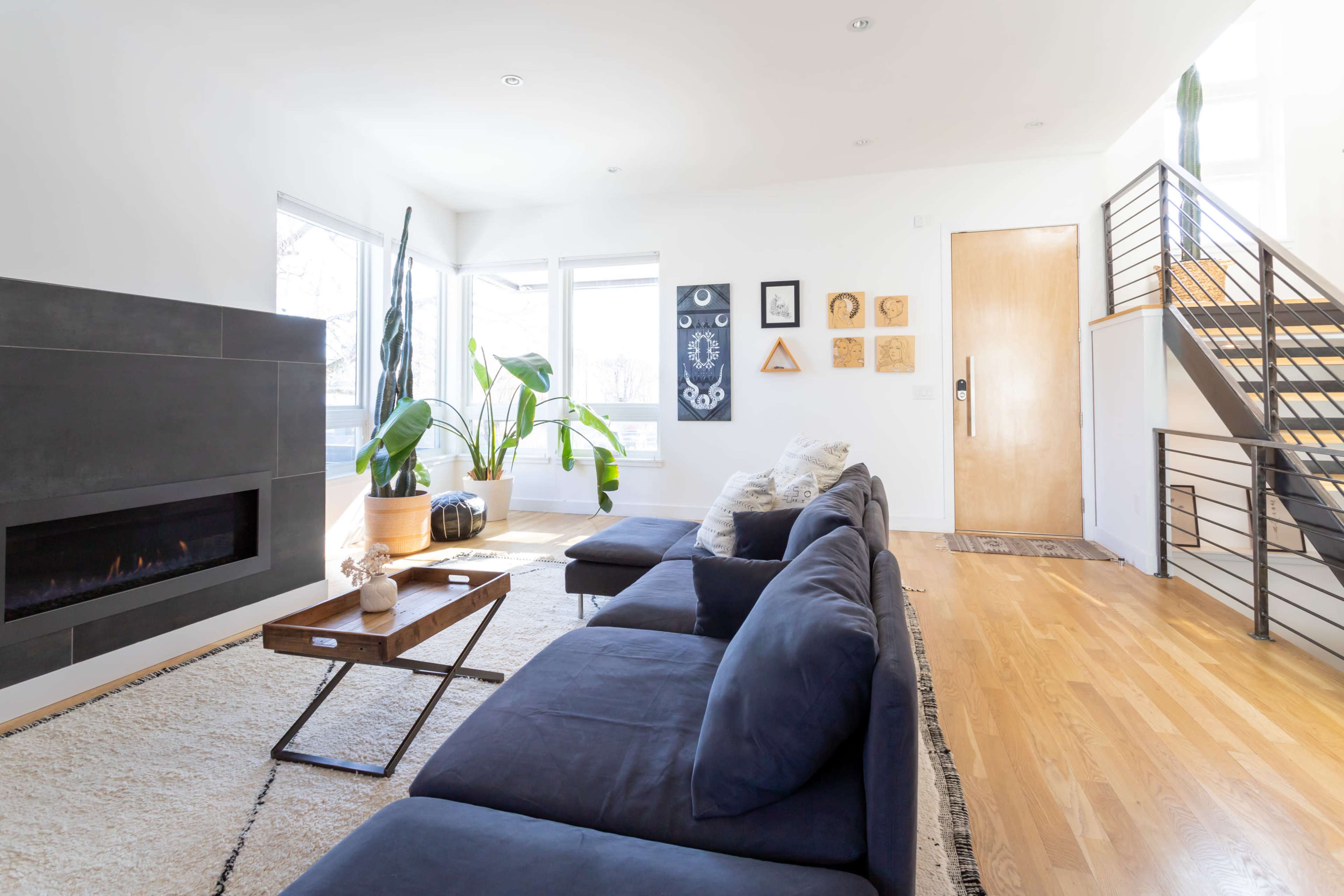 A modern living room with a cozy sofa set, a coffee table, and a staircase leading to an upper level.