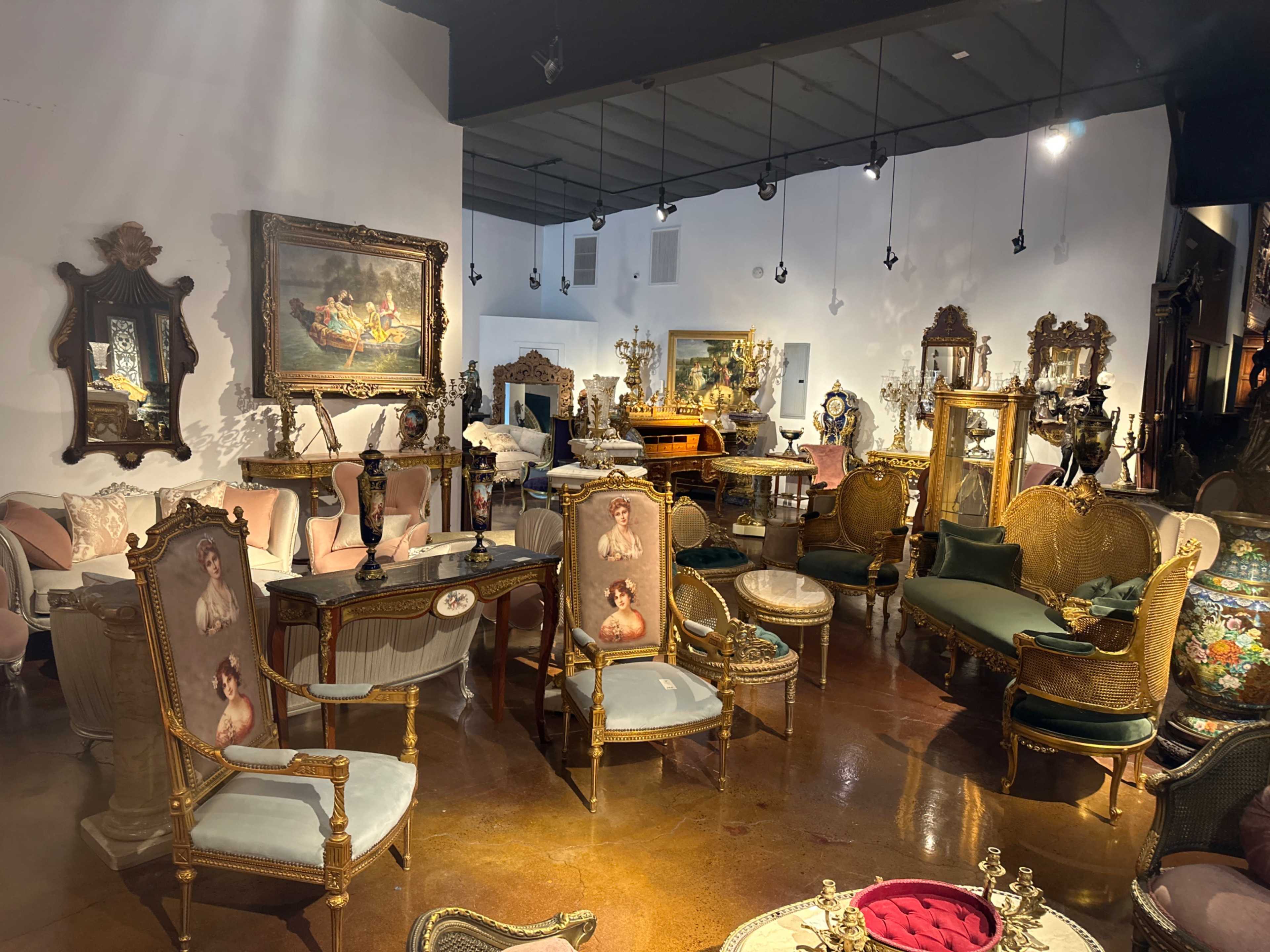 An elegantly arranged antique furniture showroom filled with various ornate chairs, tables, and decorative pieces.