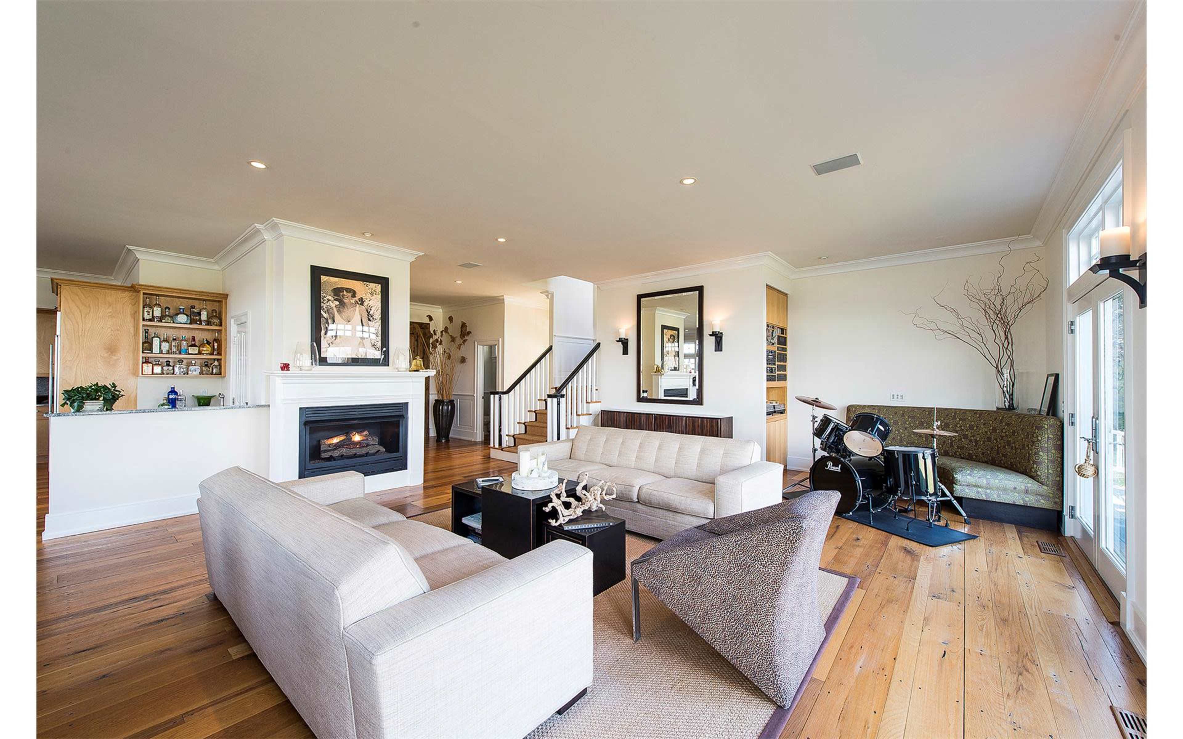 A spacious living room with a fireplace, seating area, and a small dining or entertainment nook adjacent to the kitchen.