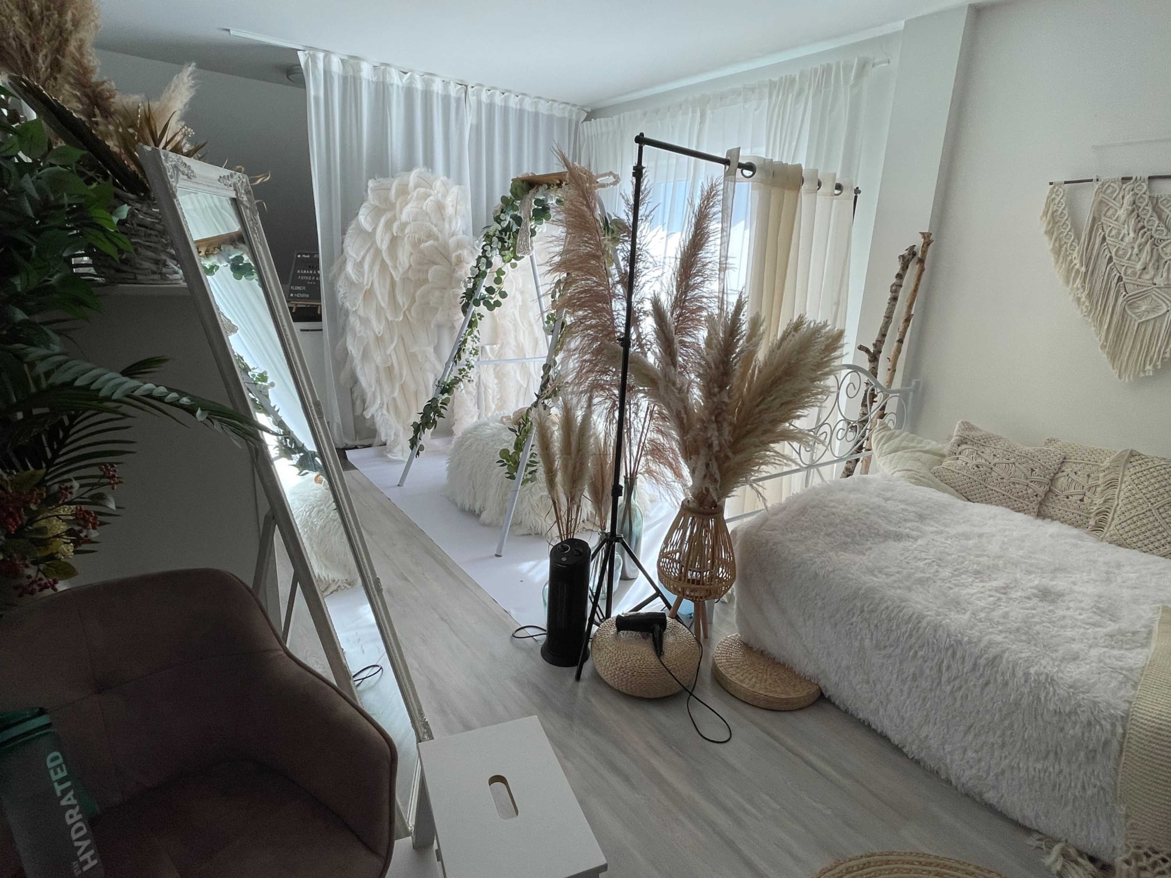 The image shows a stylish, well-decorated room featuring a bed, a large mirror, and various decorative elements including plants and textured fabrics.