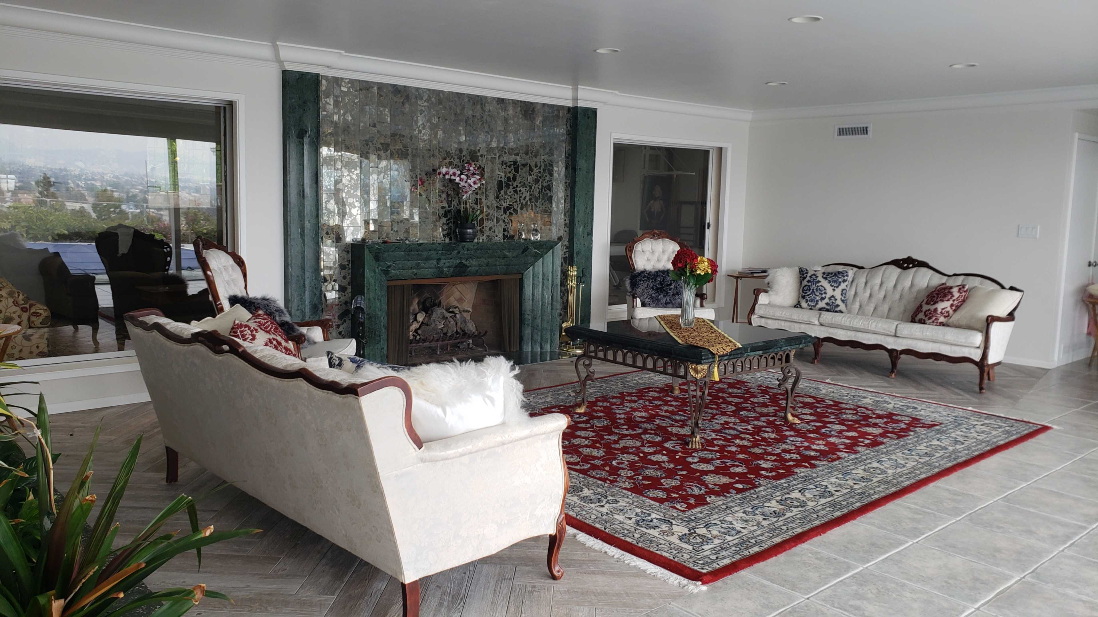 A modern living room with a green marble fireplace, two upholstered sofas, a coffee table, and a decorative area rug.