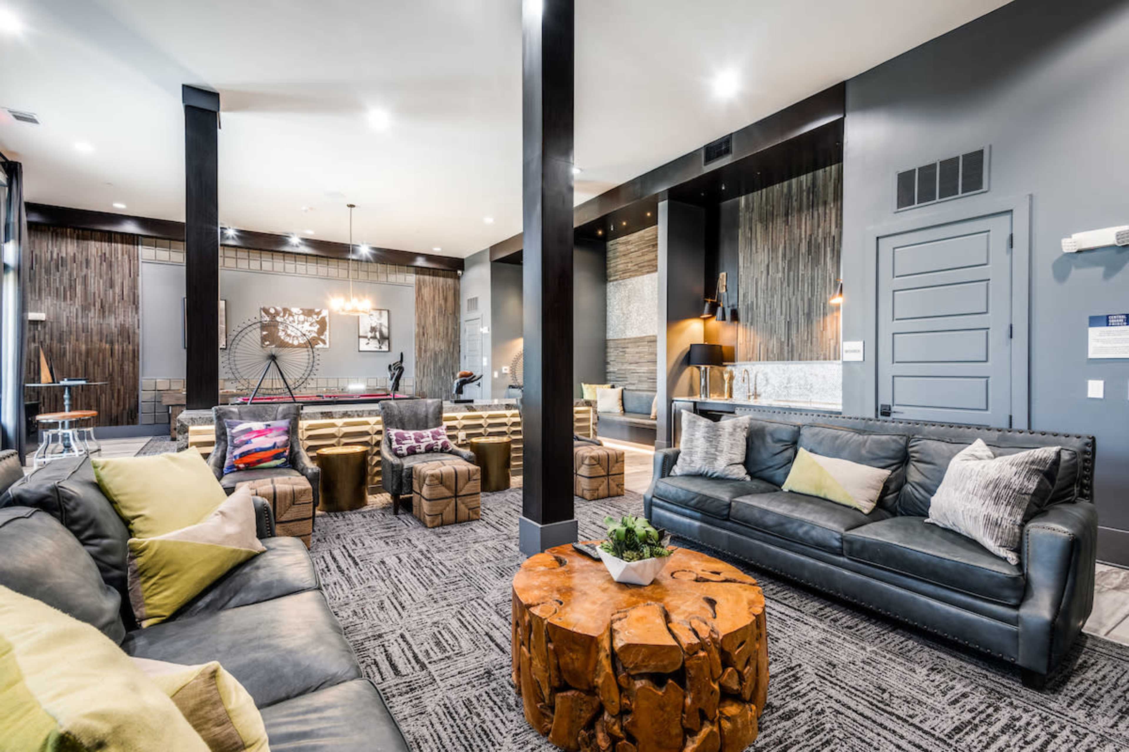 A modern lounge area features leather seating, natural wood accents, and a pool table in the background.
