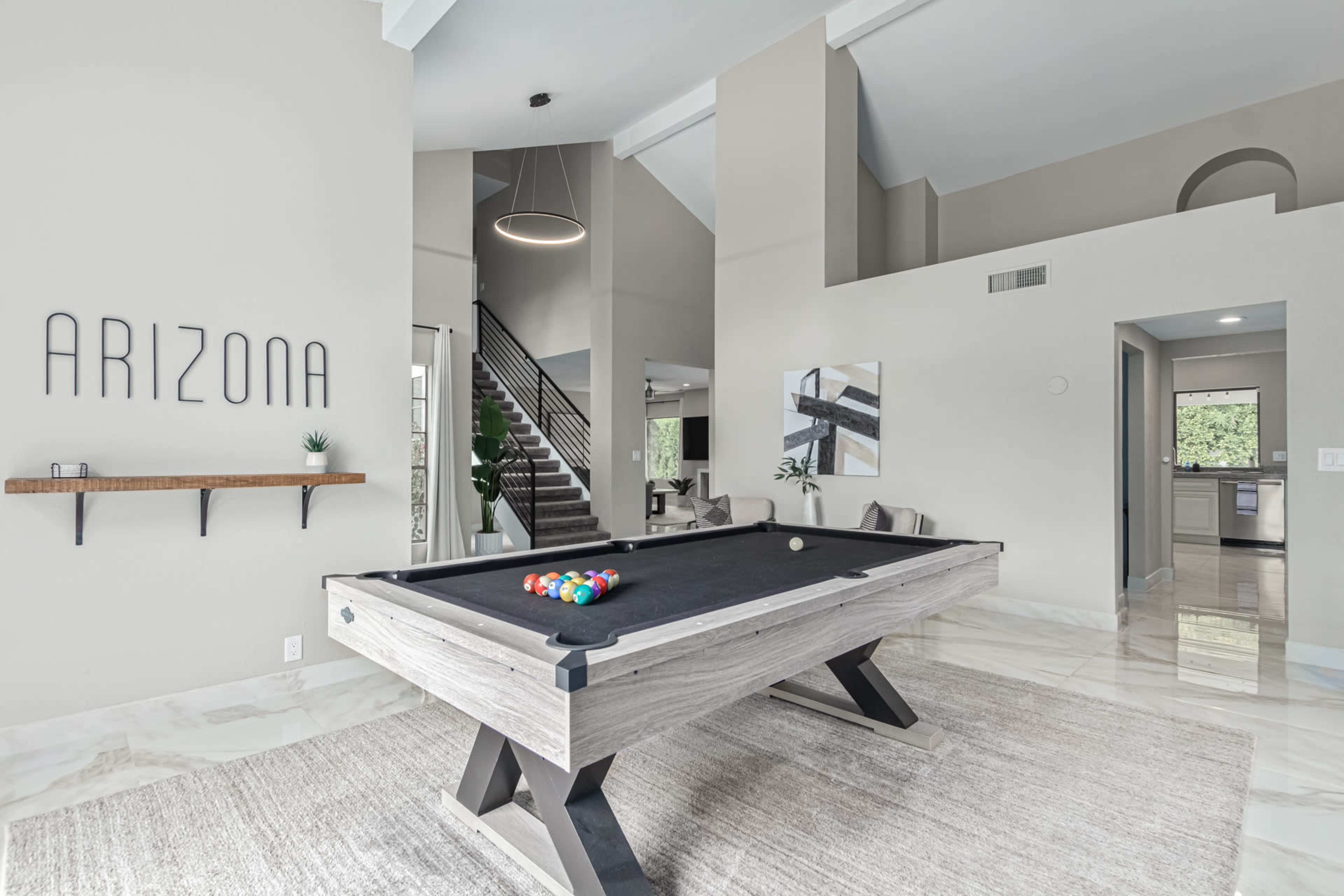 A modern game room with a billiard table and a wall displaying the word "ARIZONA."