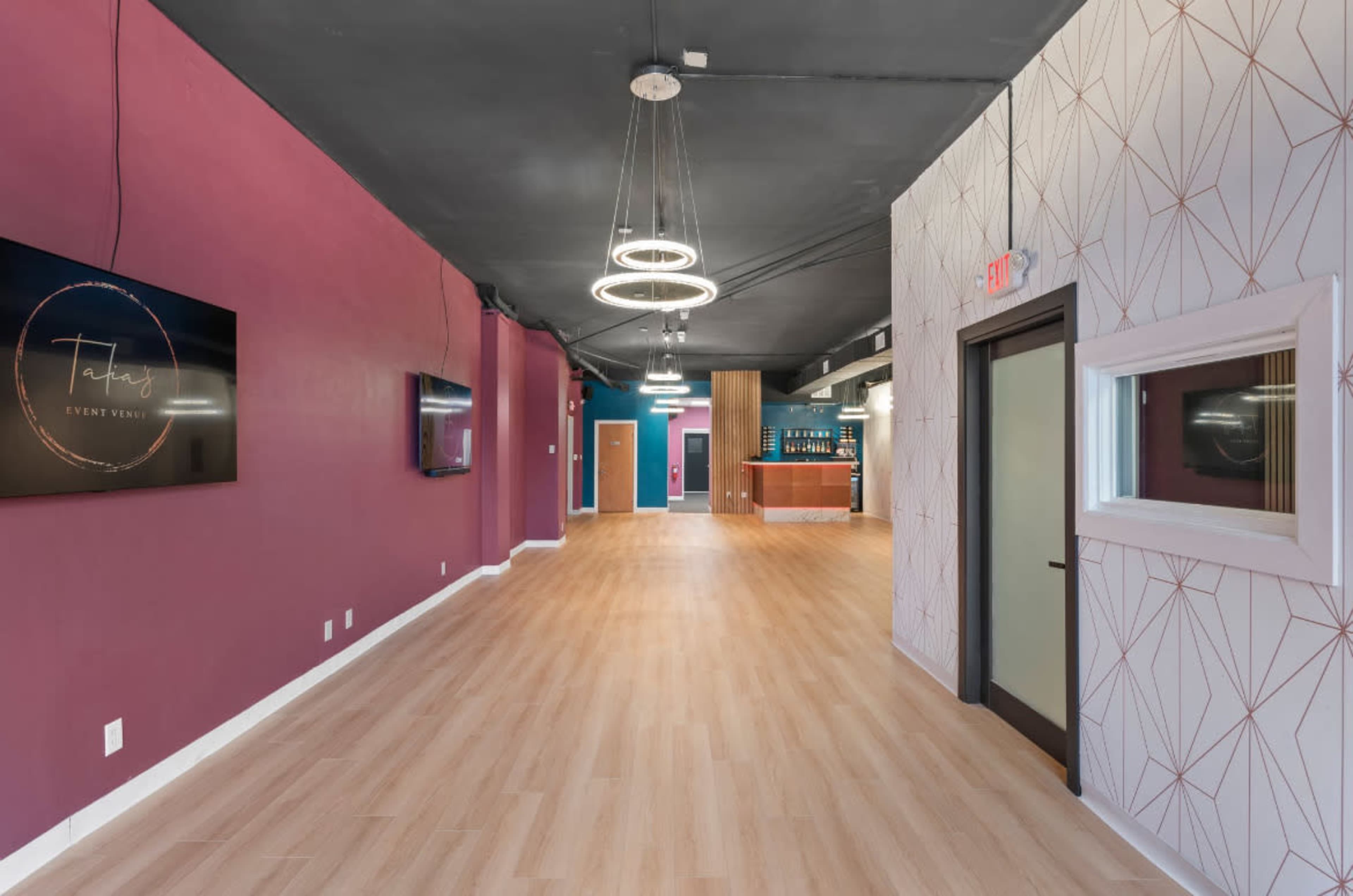 The image shows a brightly lit interior hallway with purple and white walls, modern lighting fixtures, and a reception area visible at the end.