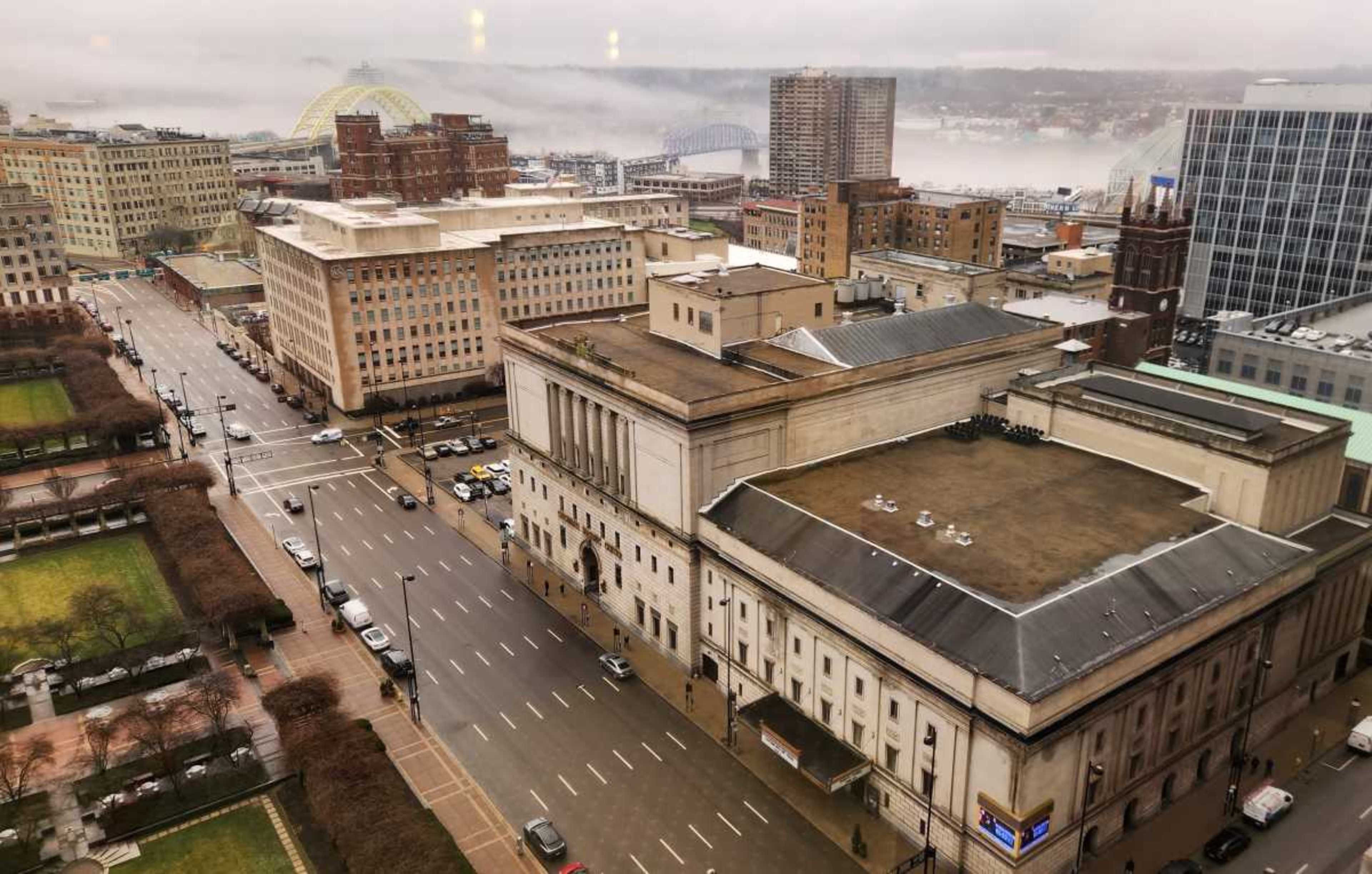 A cityscape view featuring a mix of residential and commercial buildings, with a fog-covered river and bridges in the background.