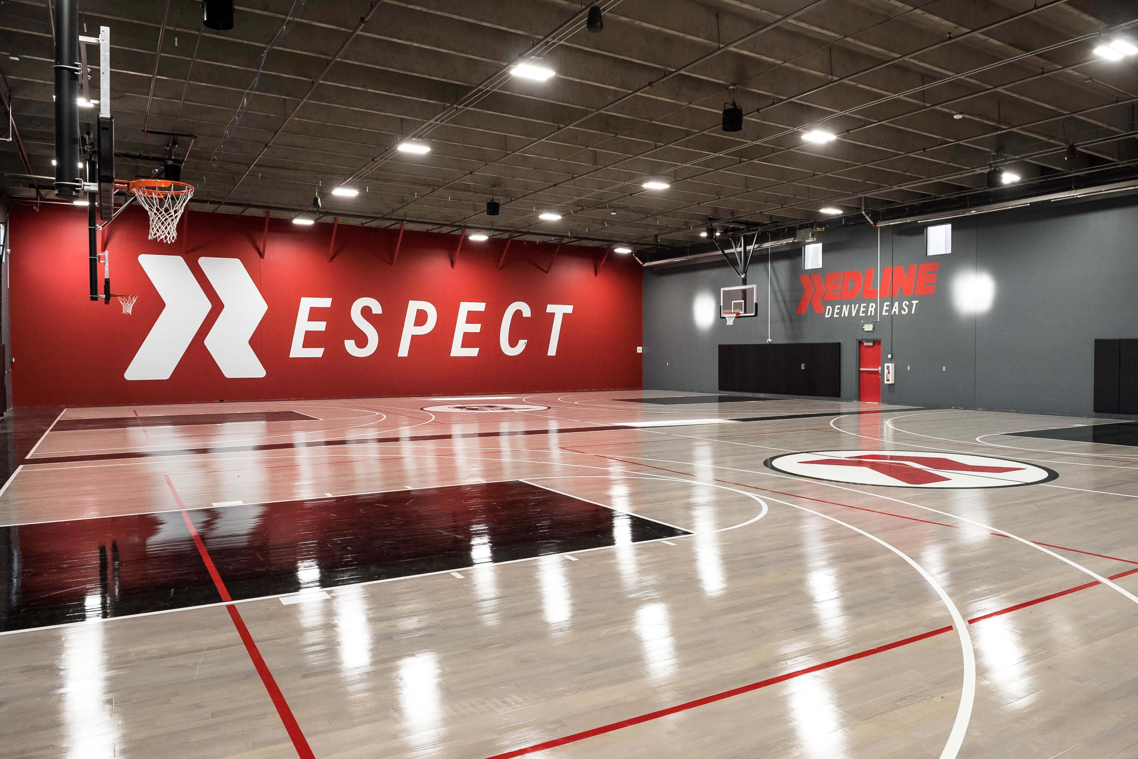 The image depicts a spacious indoor basketball court featuring a prominent "RESPECT" mural on one wall and a "REDLINE DENVER EAST" sign on the adjacent wall.