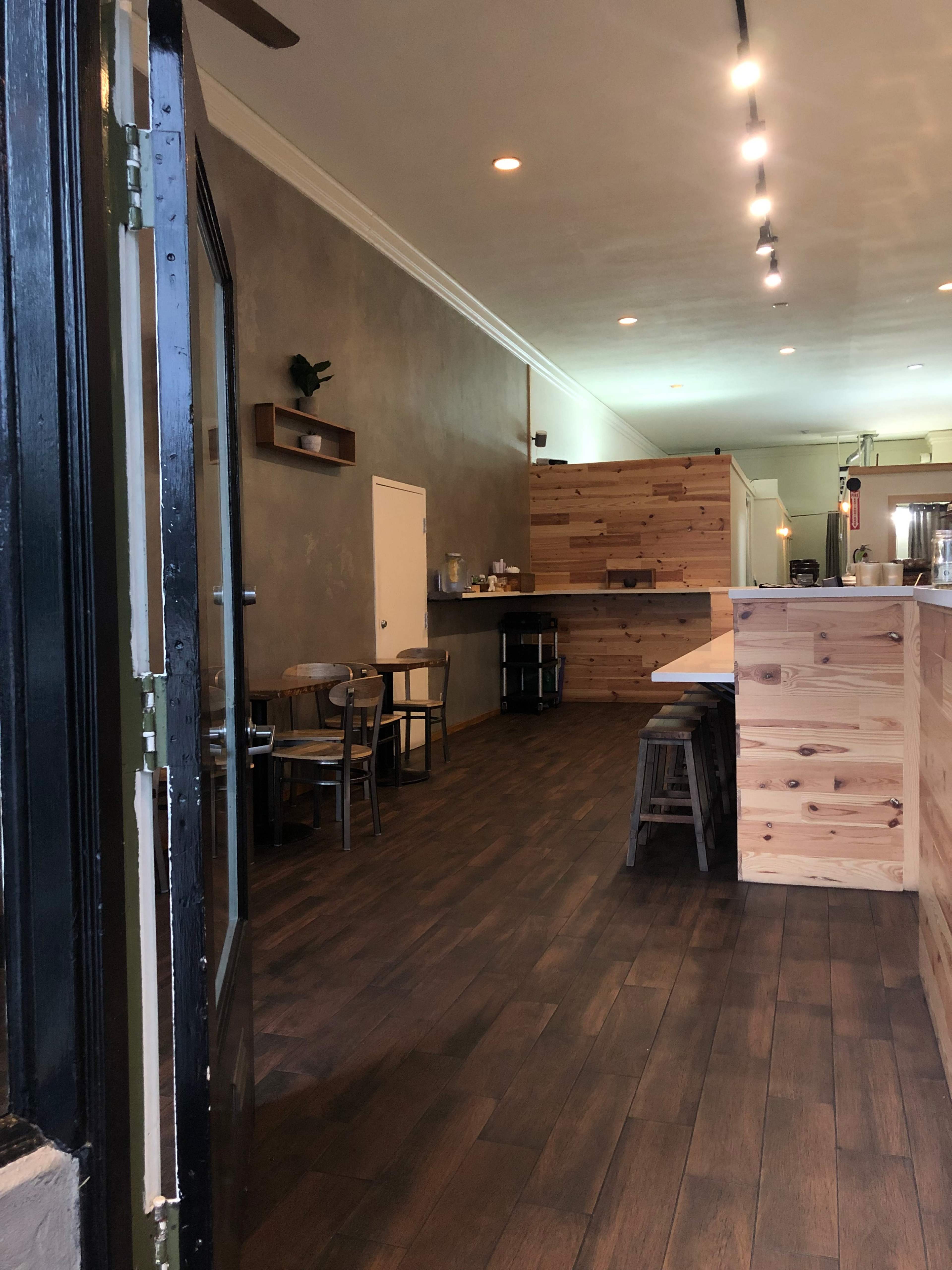 The interior of a café featuring wooden furniture, a counter made of wooden planks, and a gray wall.