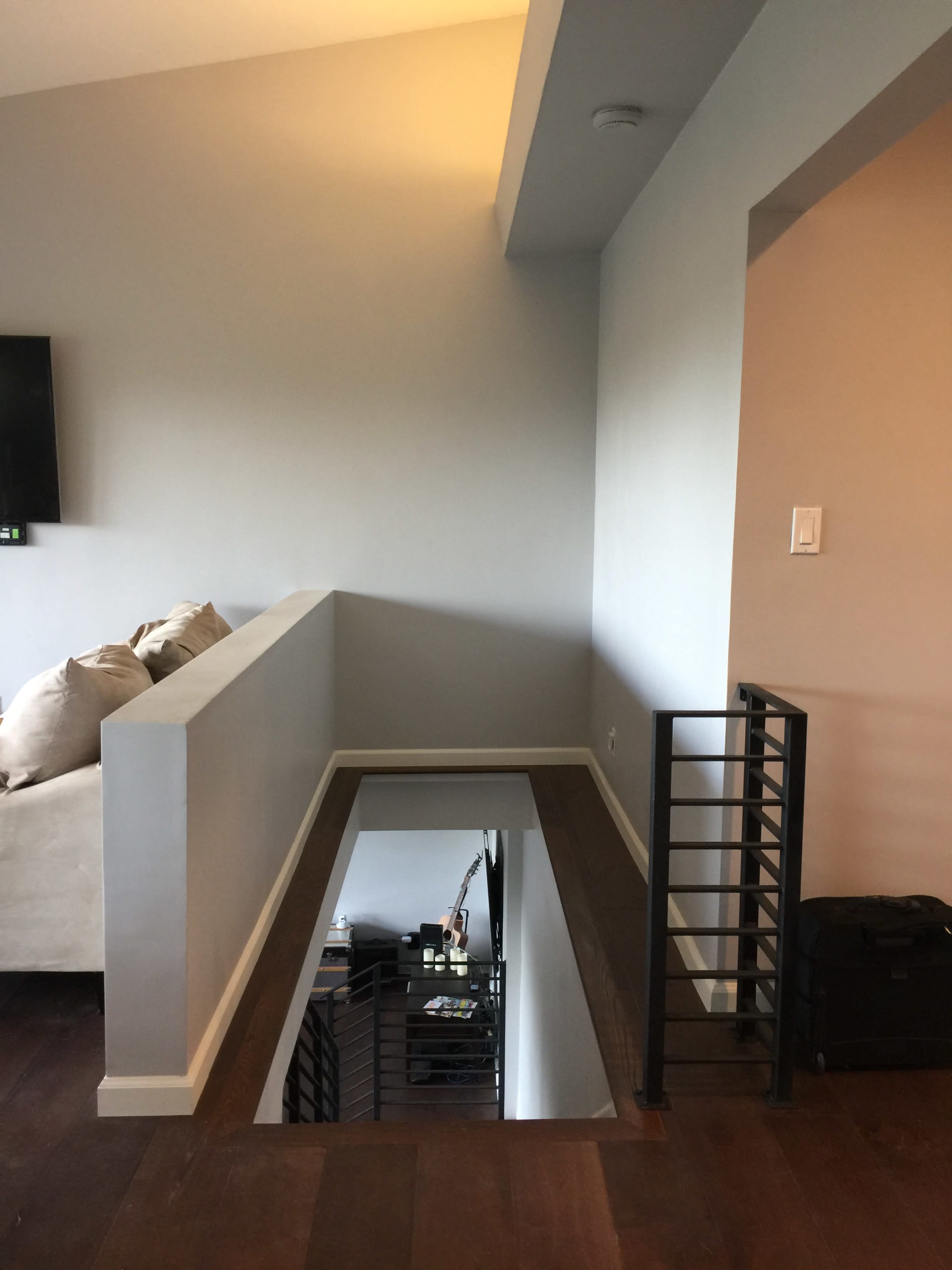 The image shows a second-floor landing with a railing overlooking a staircase.