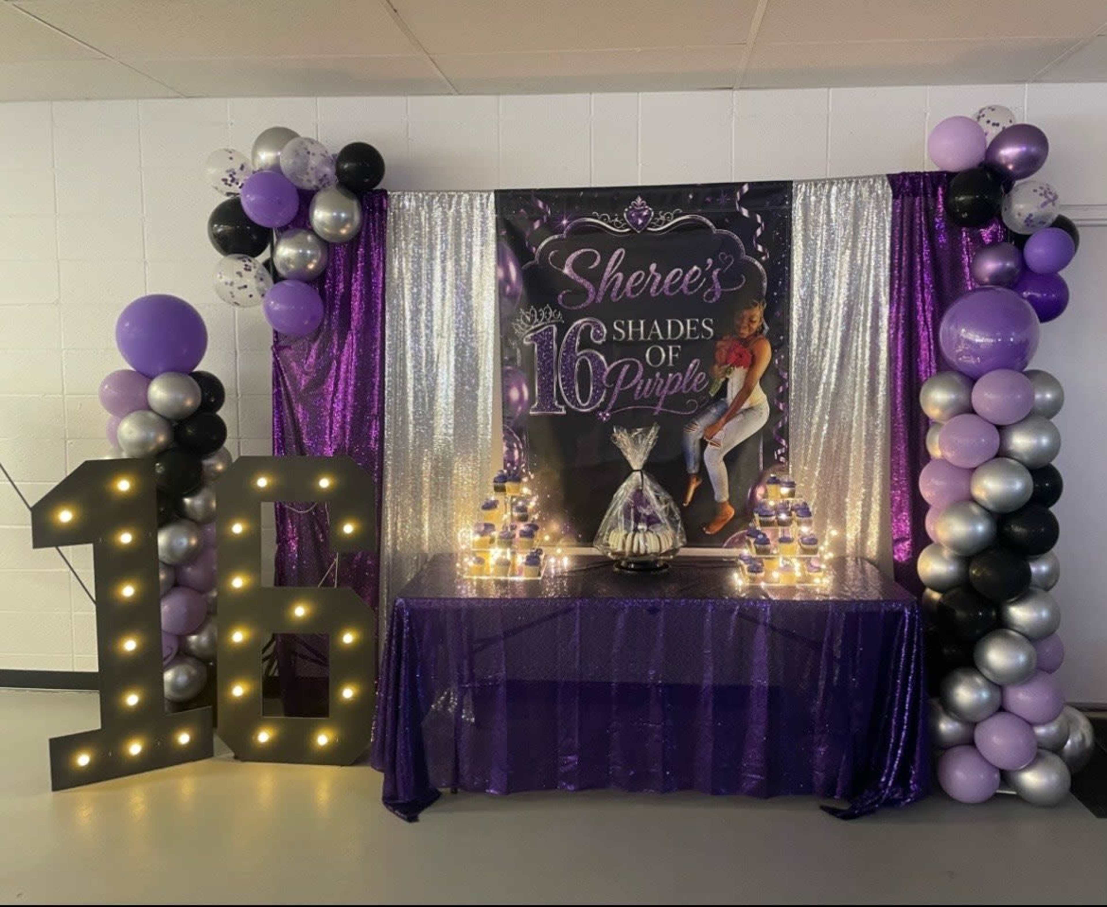 The image shows a festive decor setup for a sweet sixteen celebration, featuring purple and silver balloons, a backdrop with the text "Sheree's Shades of Purple," and a decorated table with a tiered cake and candles.