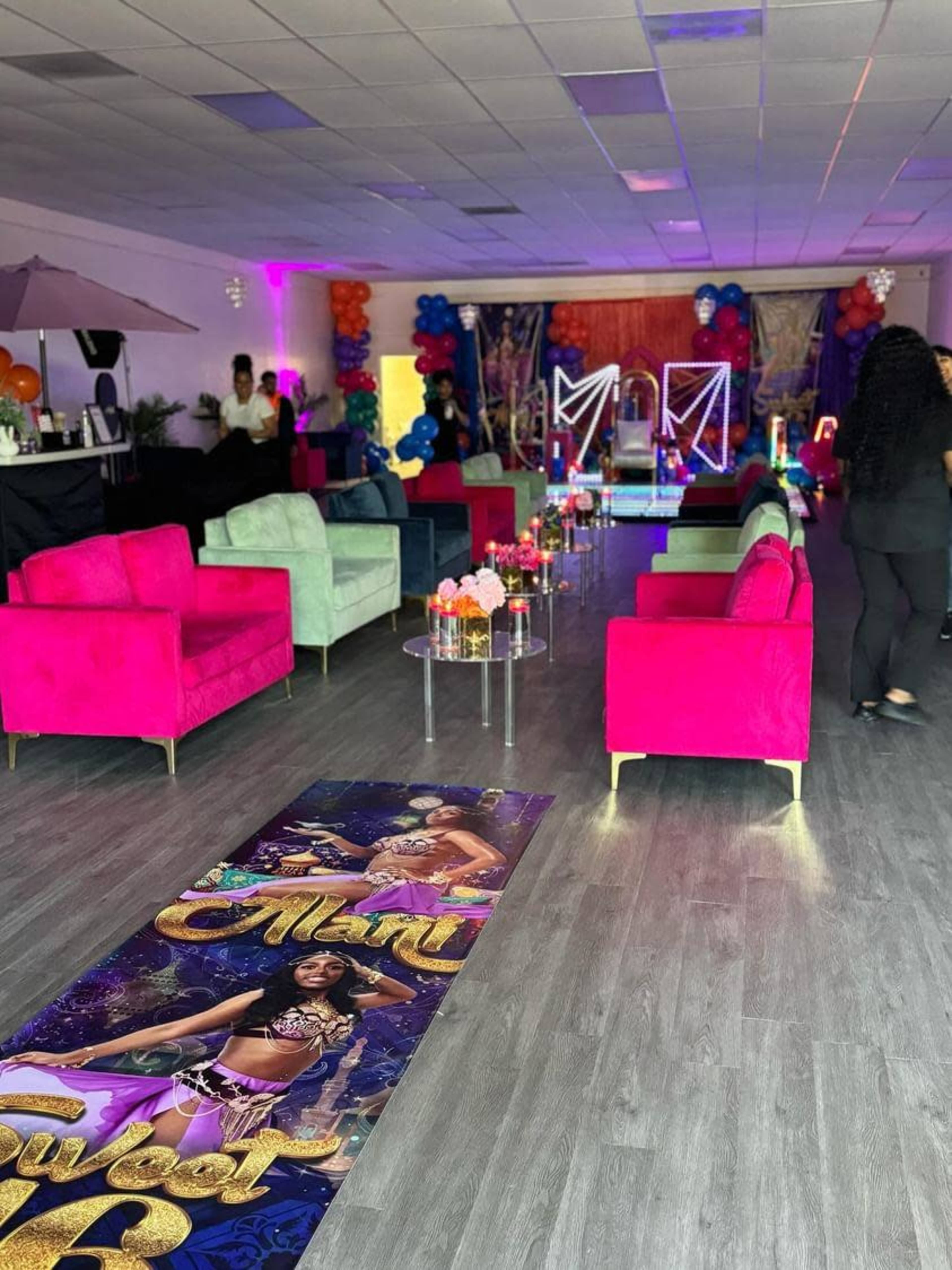 A vibrantly decorated event space with colorful couches, a dance area, and a large banner featuring a performer.