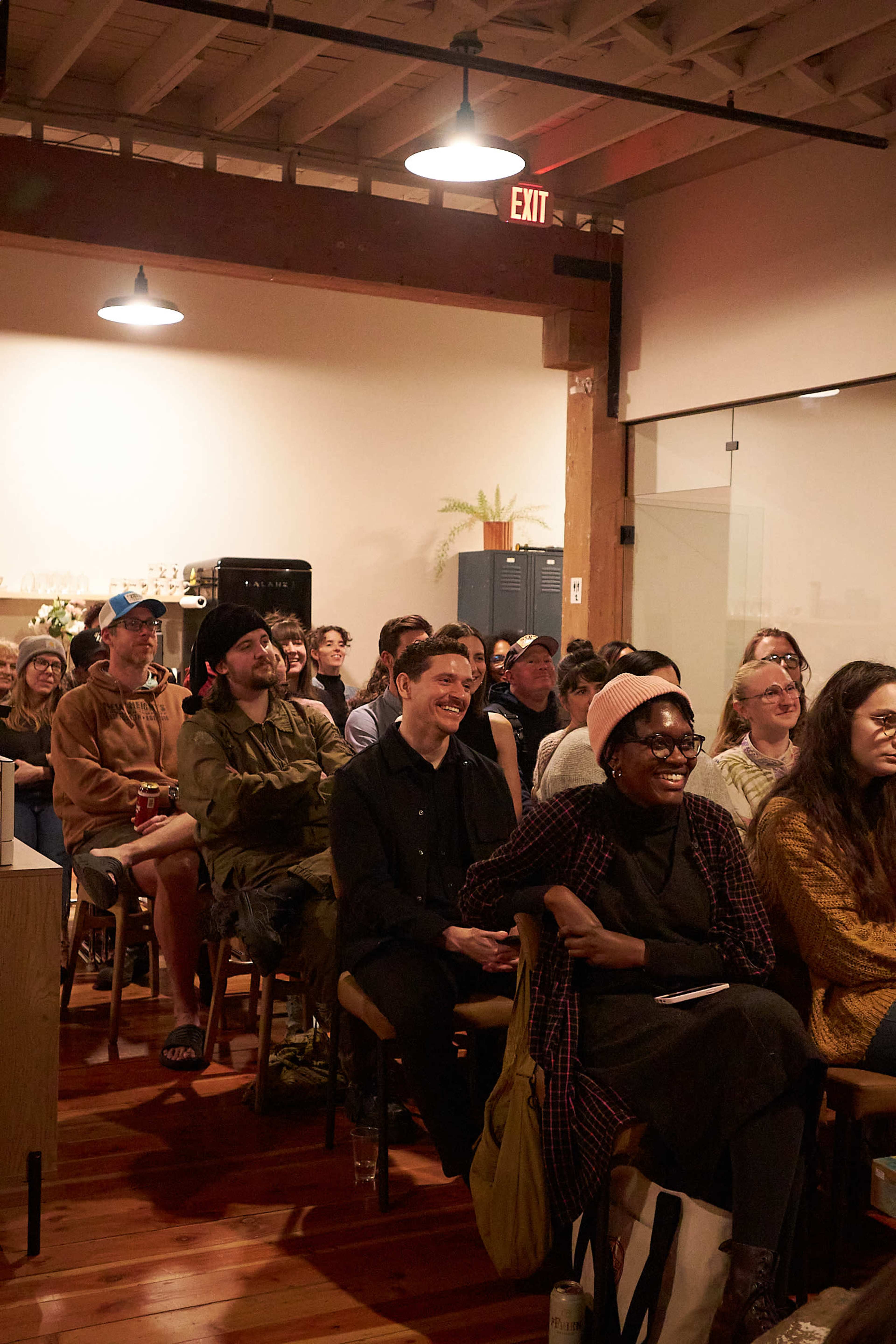 A group of people is seated in a well-lit room, attentively engaged in a presentation or event.