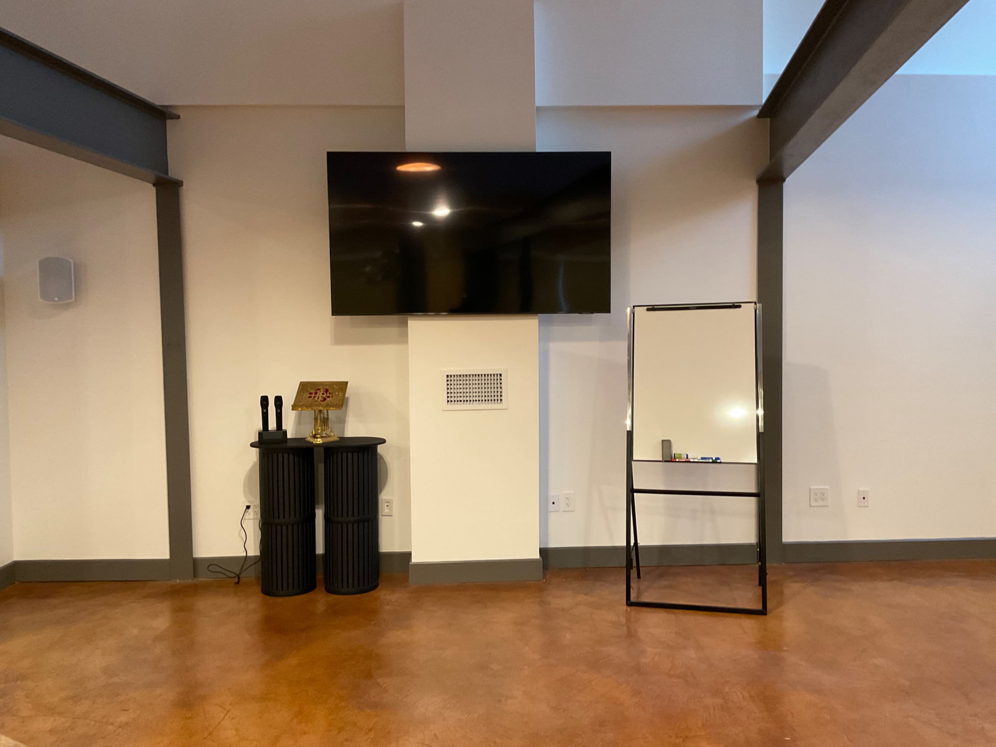 A room with a mounted TV on the wall, a black side table with decorative items, and a freestanding mirror on the right side.
