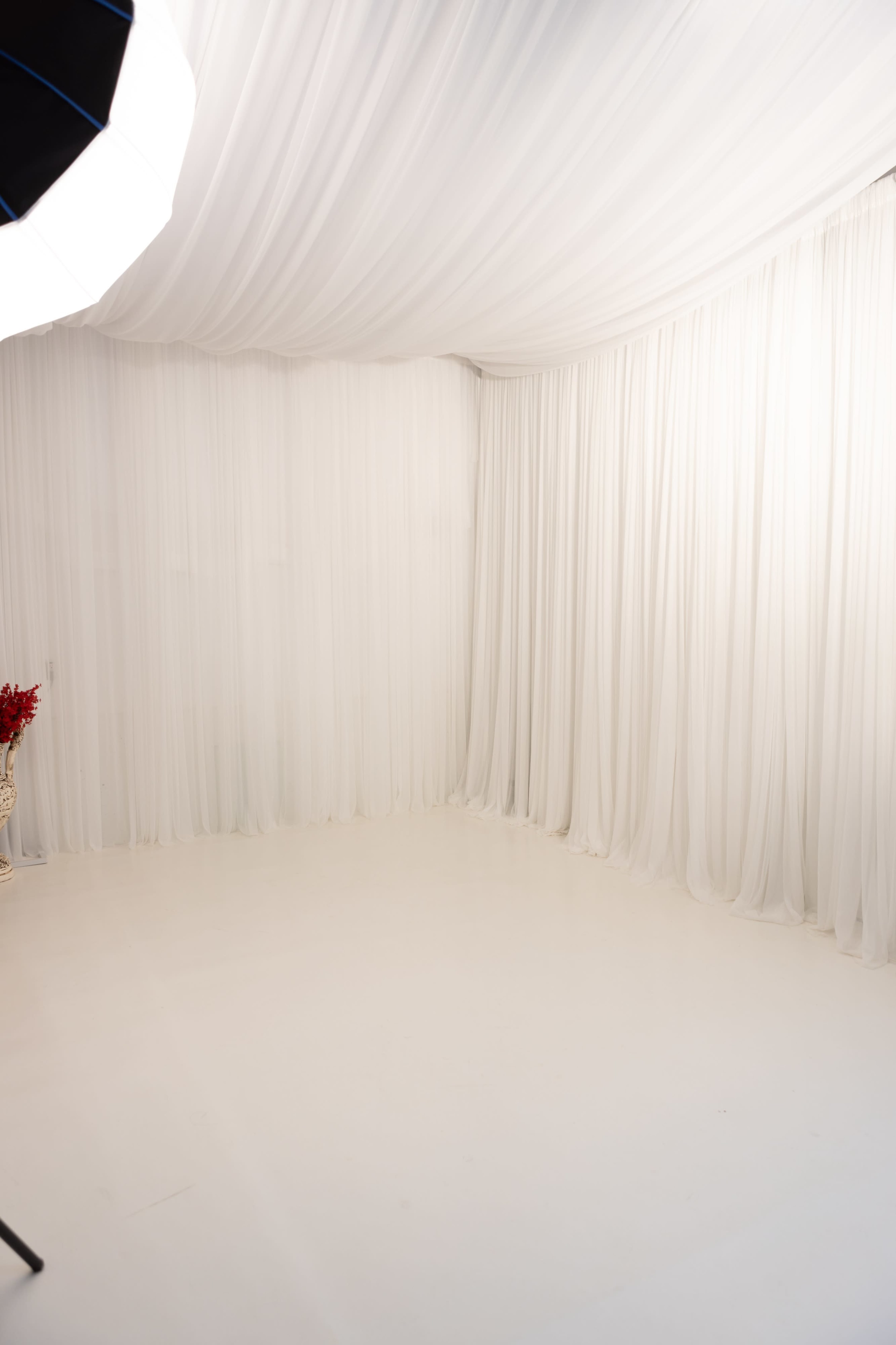 The image shows a bright studio space with white drapery and flooring, creating an expansive and uncluttered environment.