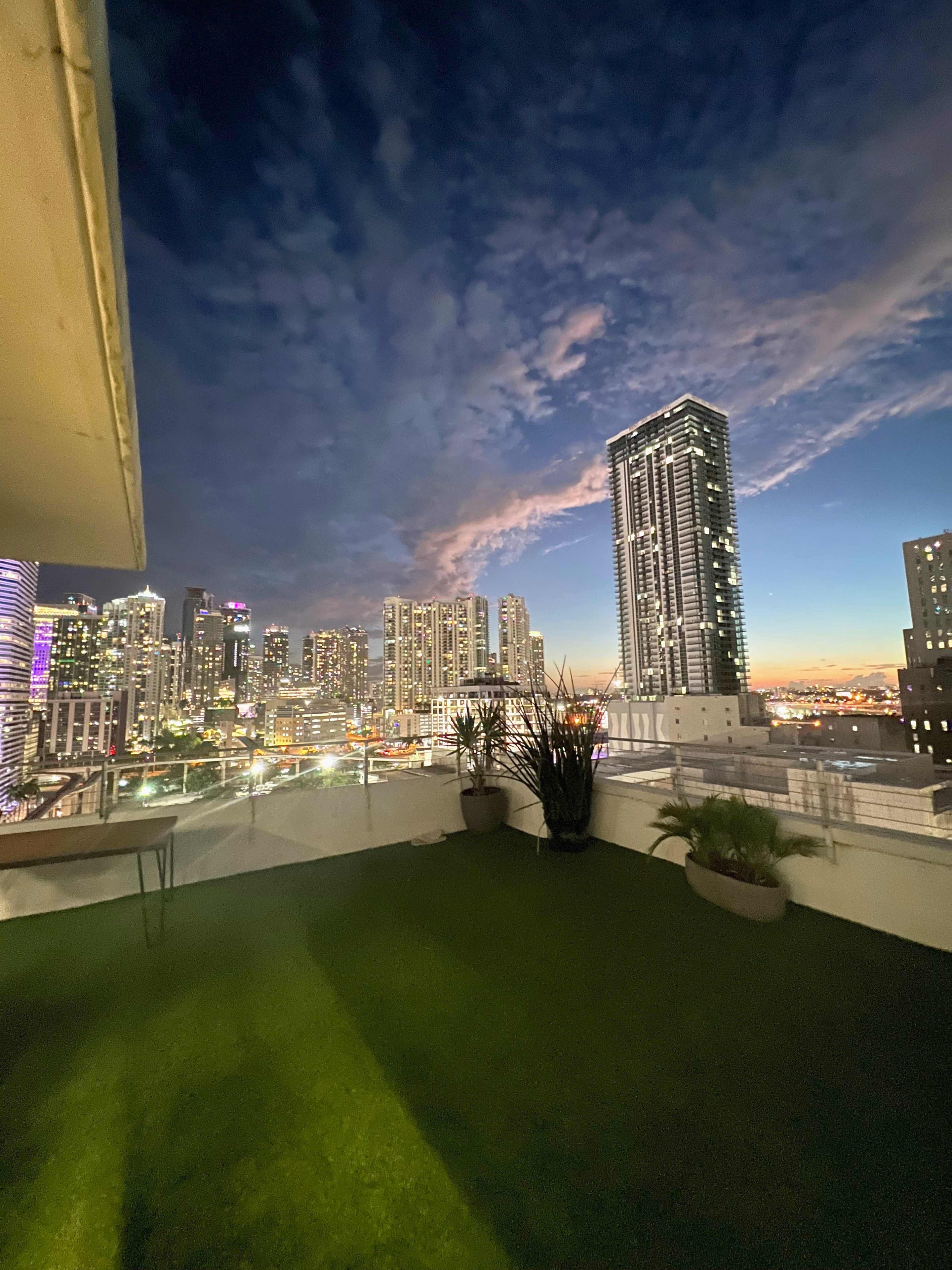 A rooftop view of a city skyline at twilight, featuring modern buildings and a colorful sky.