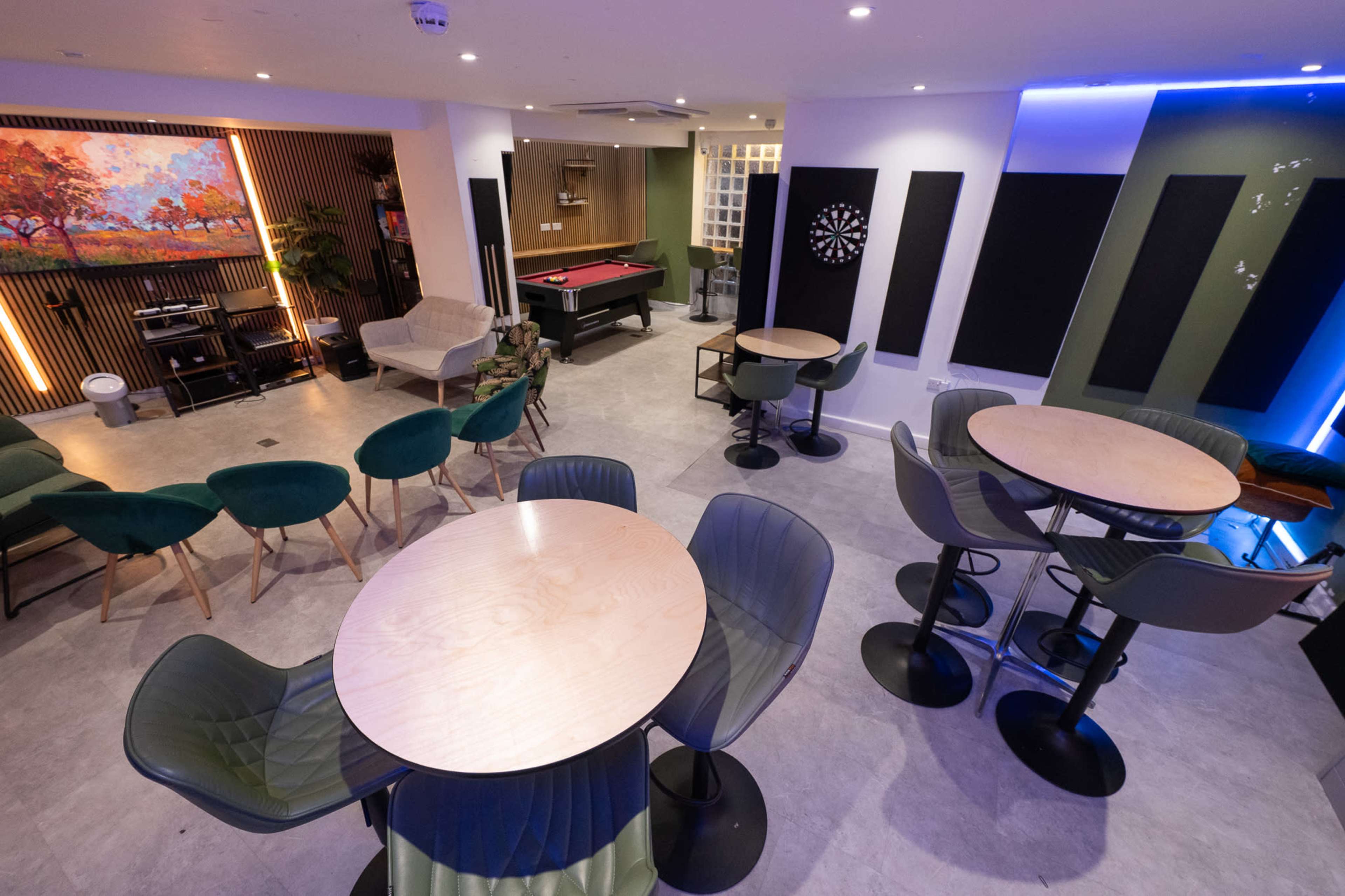 The image shows a modern lounge area with seating, a pool table, and tables arranged for socializing.