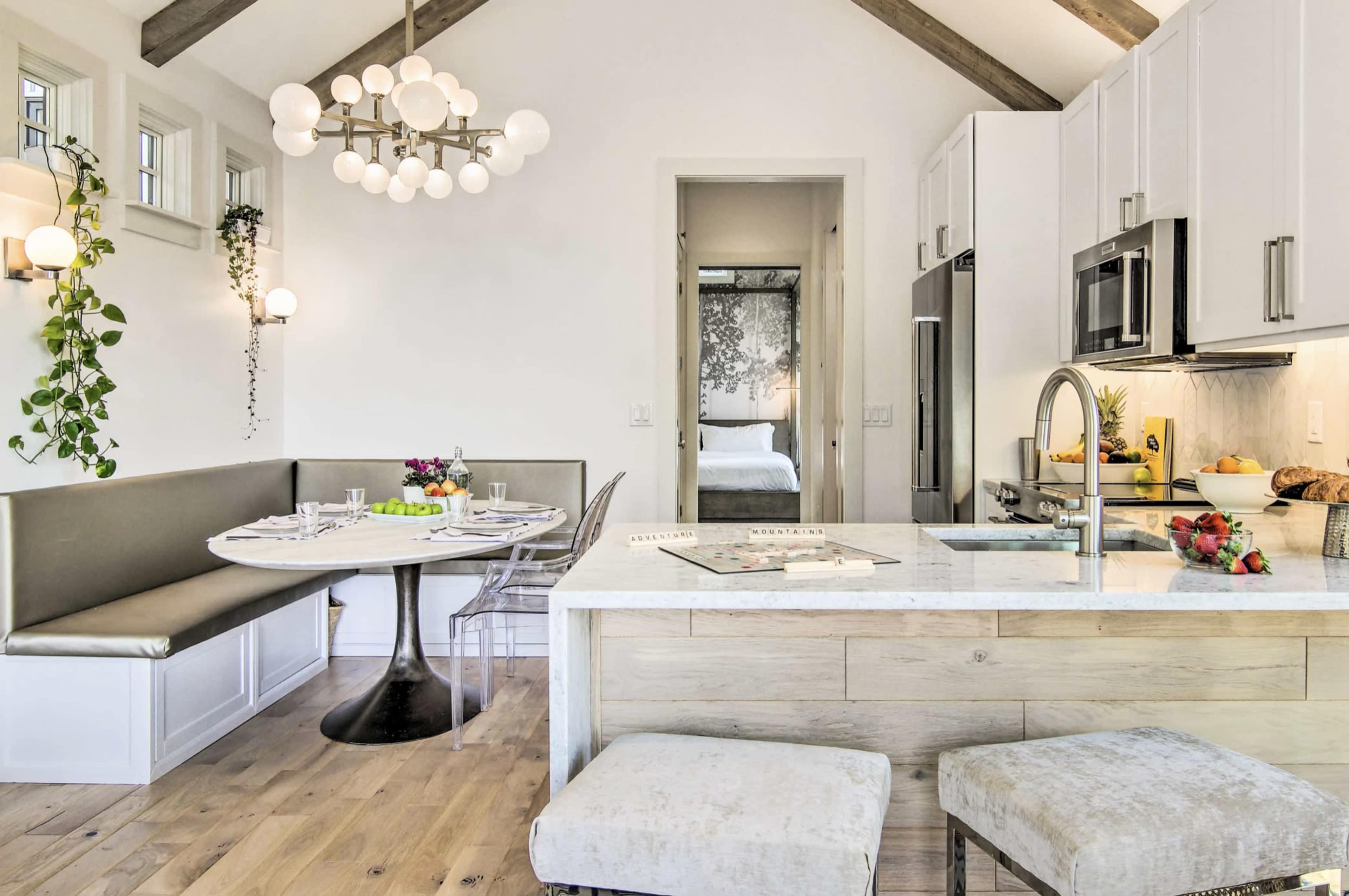 A modern kitchen and dining area feature a circular table with a built-in bench and an island with a marble countertop.