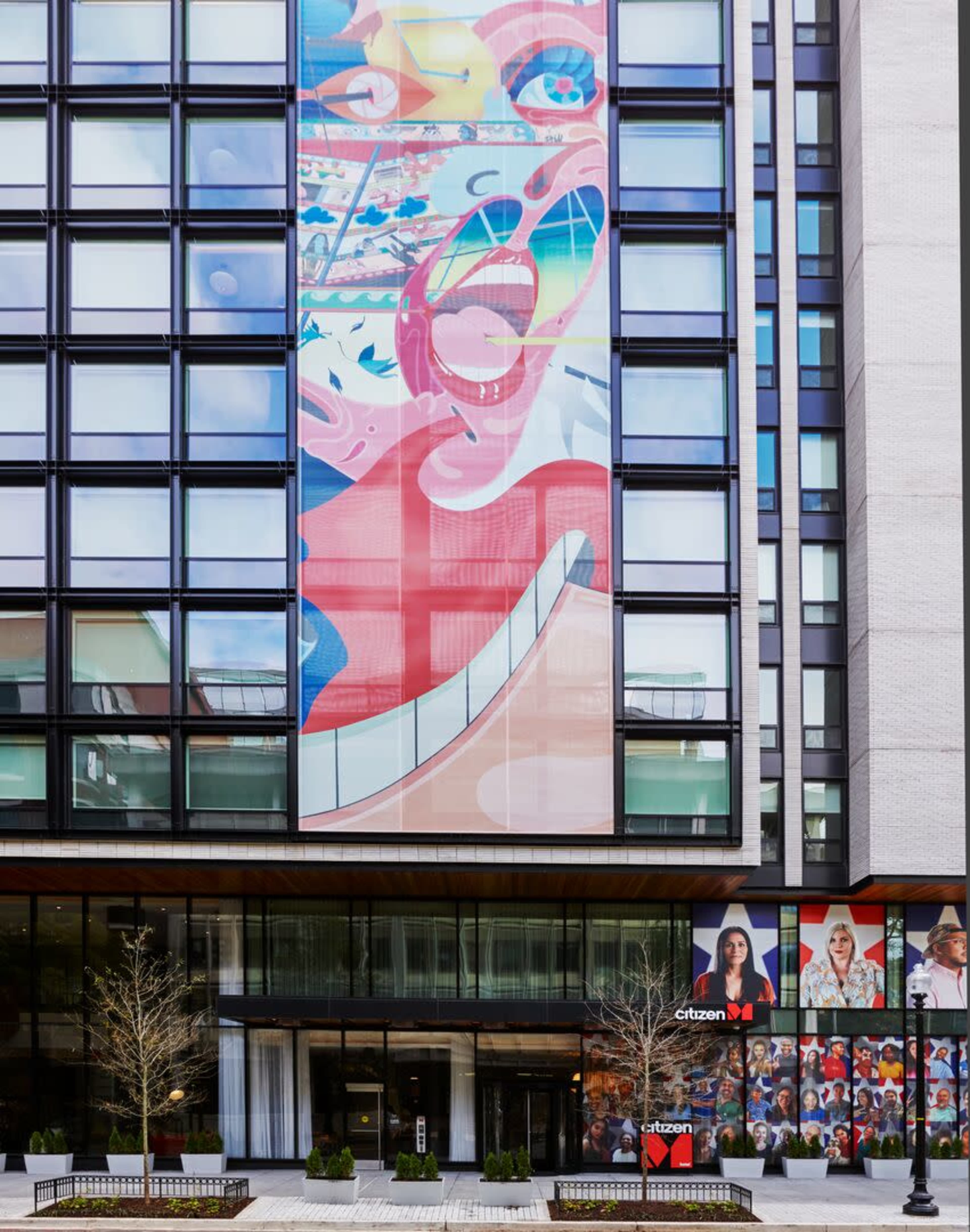 A modern building facade featuring colorful artwork and promotional visuals on its windows.