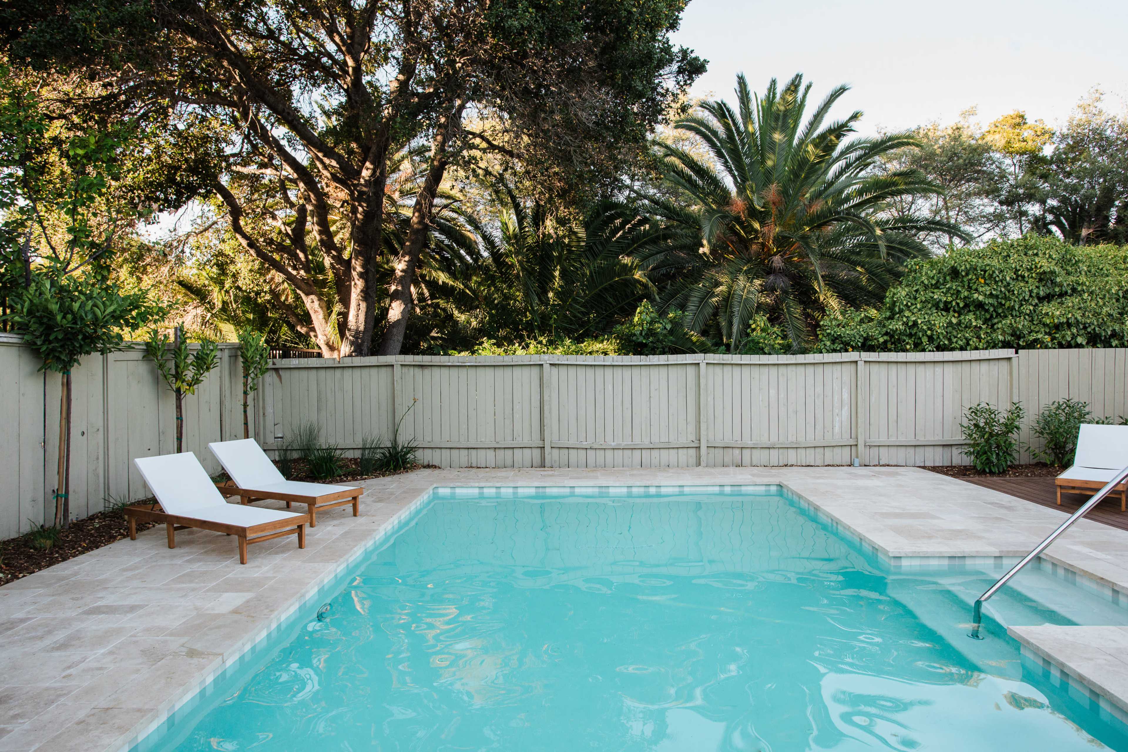 A well-maintained swimming pool surrounded by lounge chairs and lush greenery.