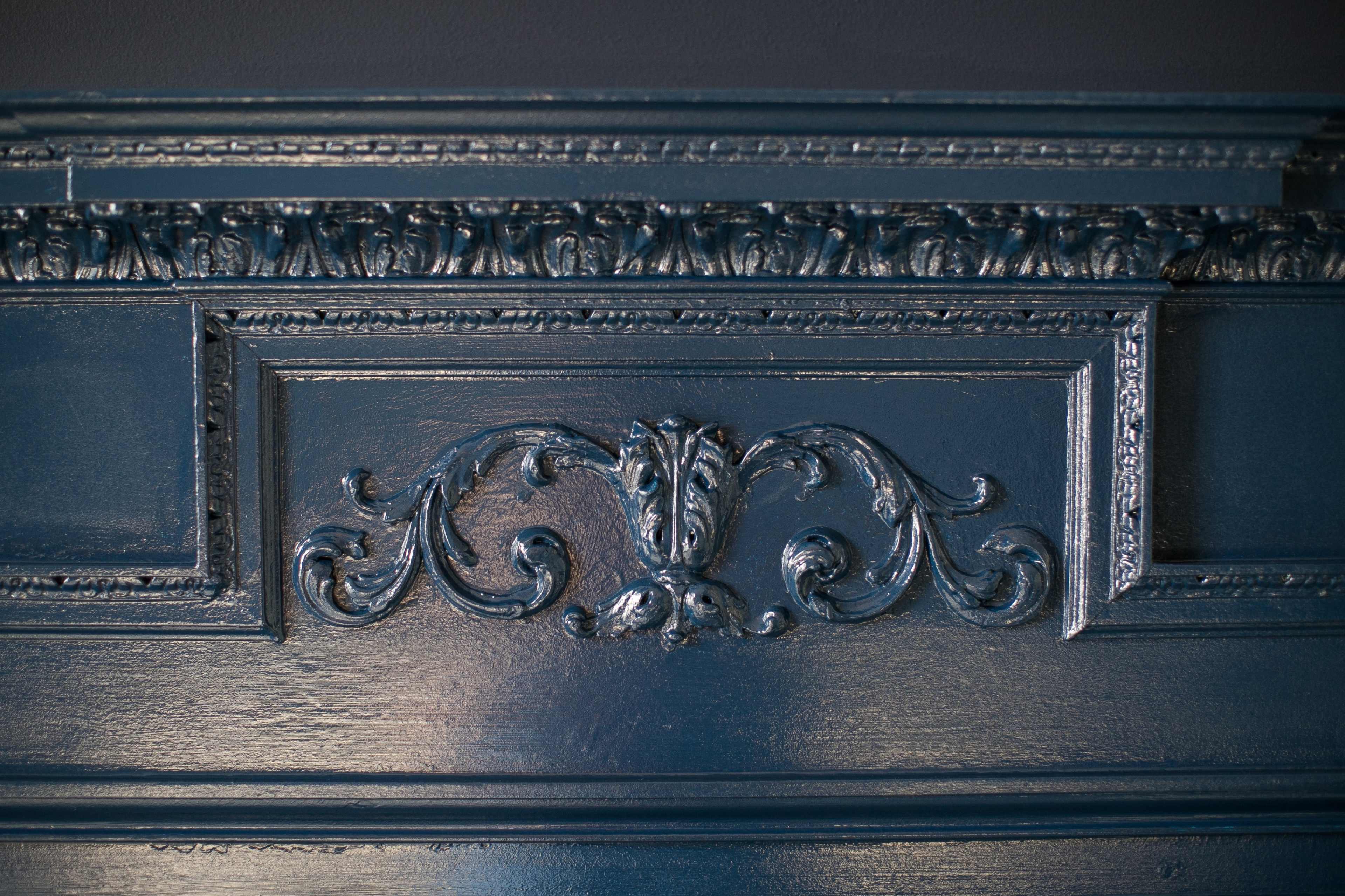 A detailed, dark blue carved wood panel featuring ornate designs.