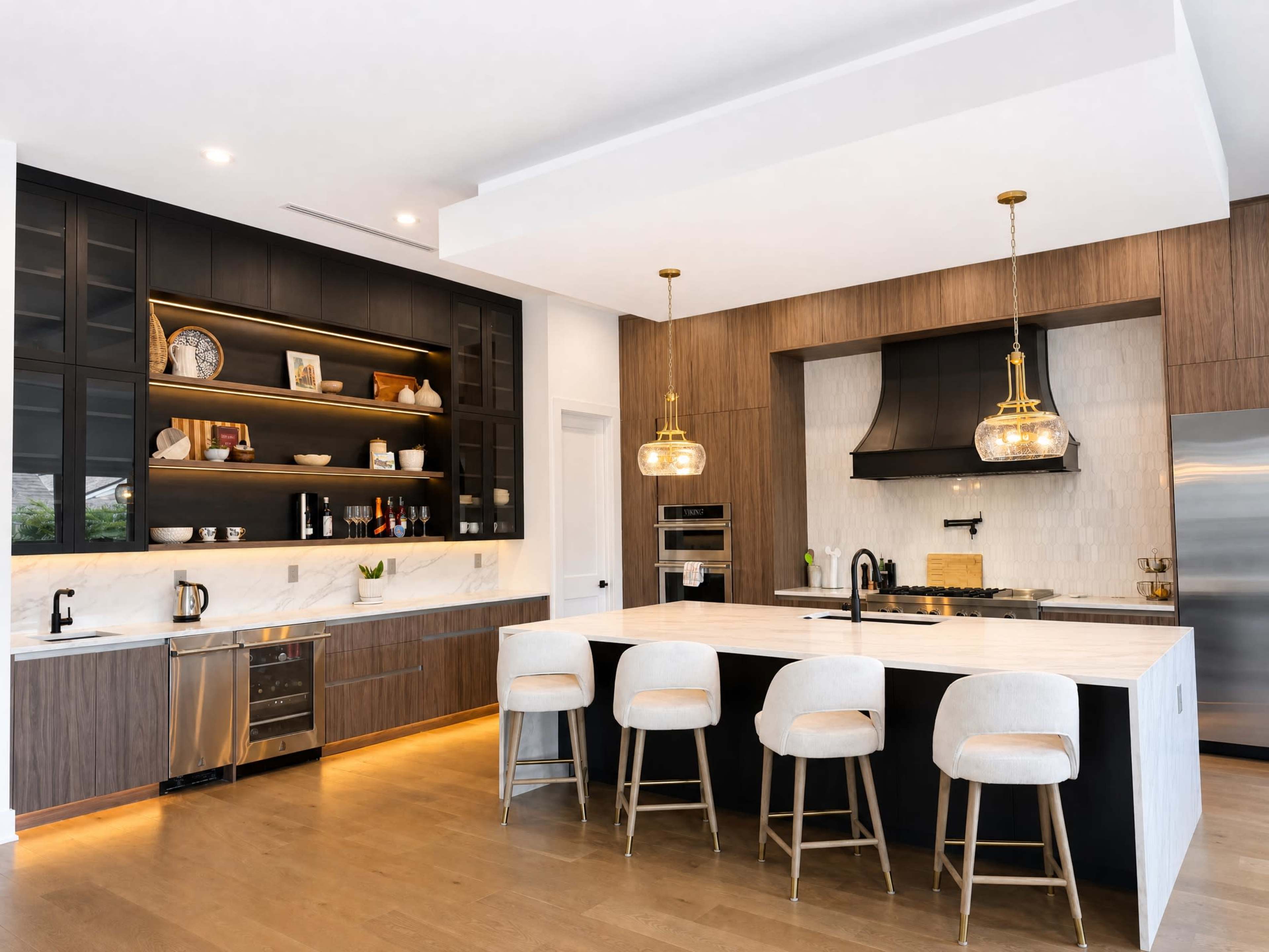 The image shows a modern kitchen featuring a central island with seating, dark cabinetry, and warm wooden accents.