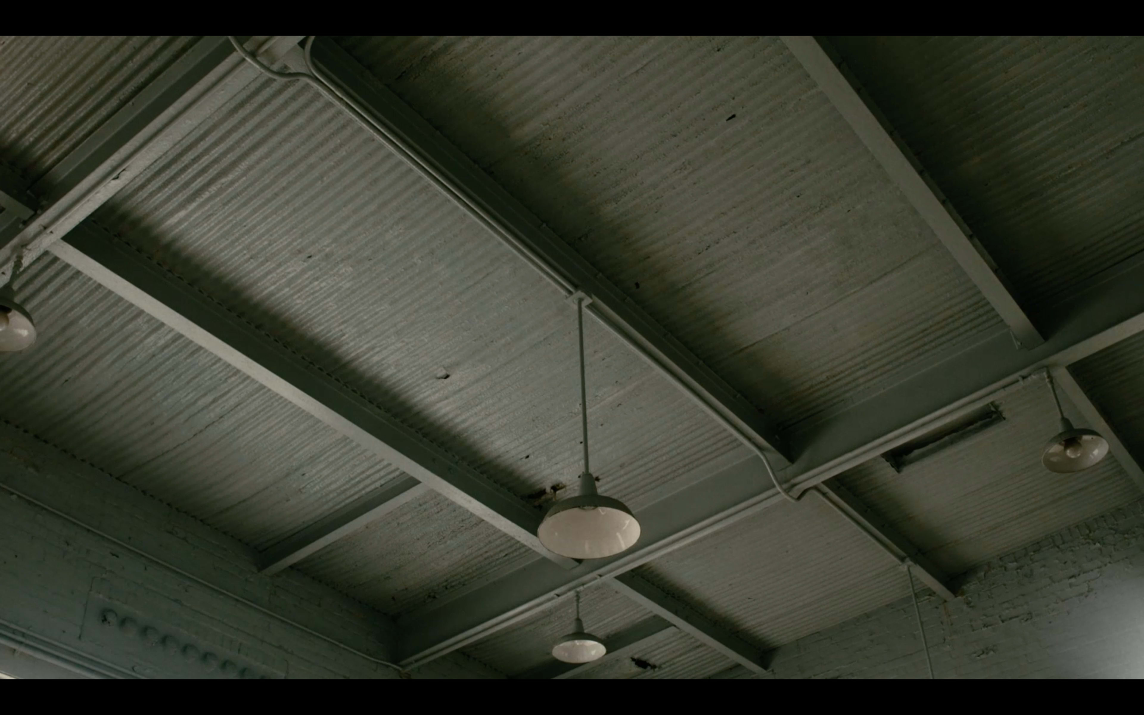 A high ceiling with exposed beams and pendant lights in a room.