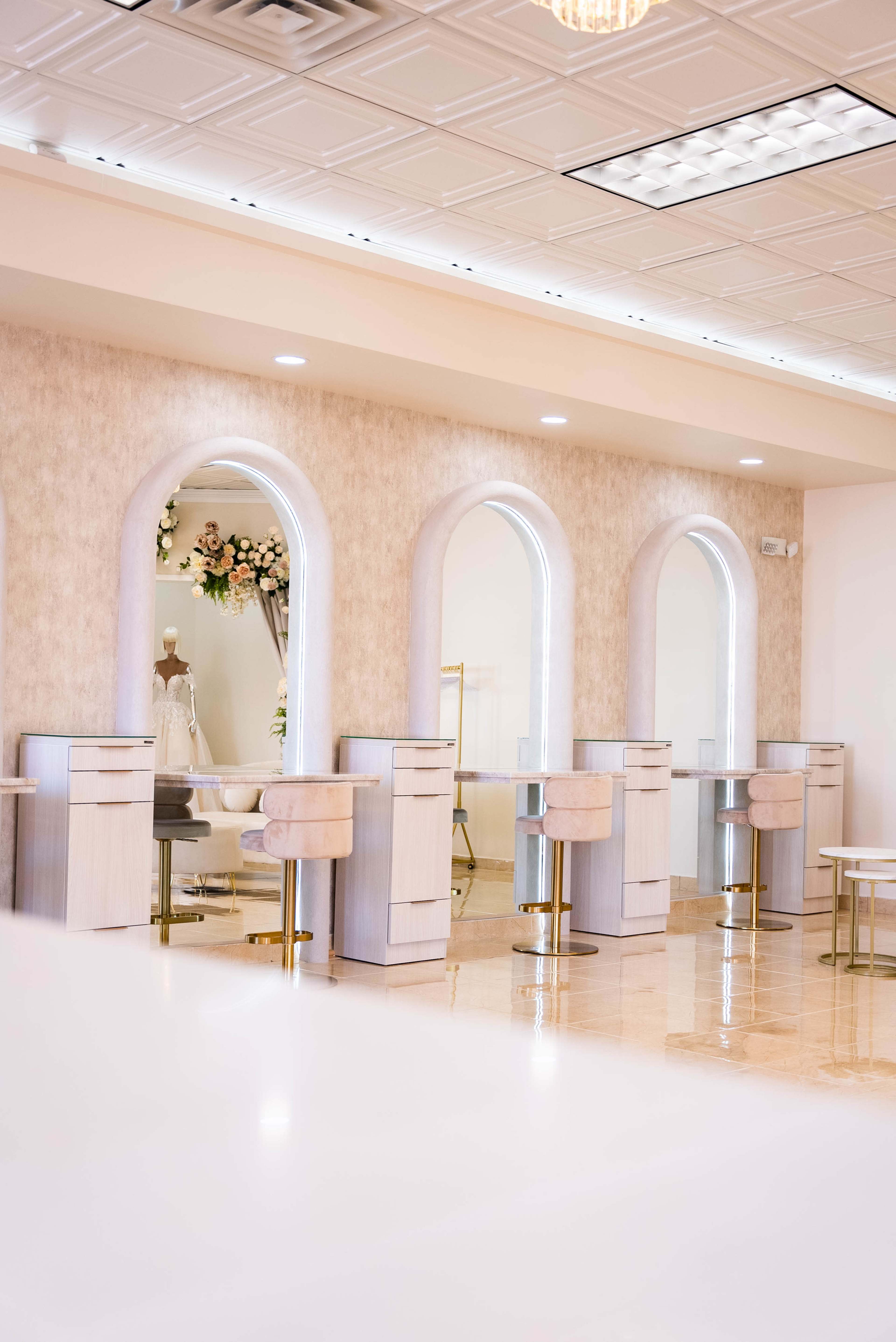 A beauty salon interior with three stylized mirrors, elegant chairs, and a soft color palette.