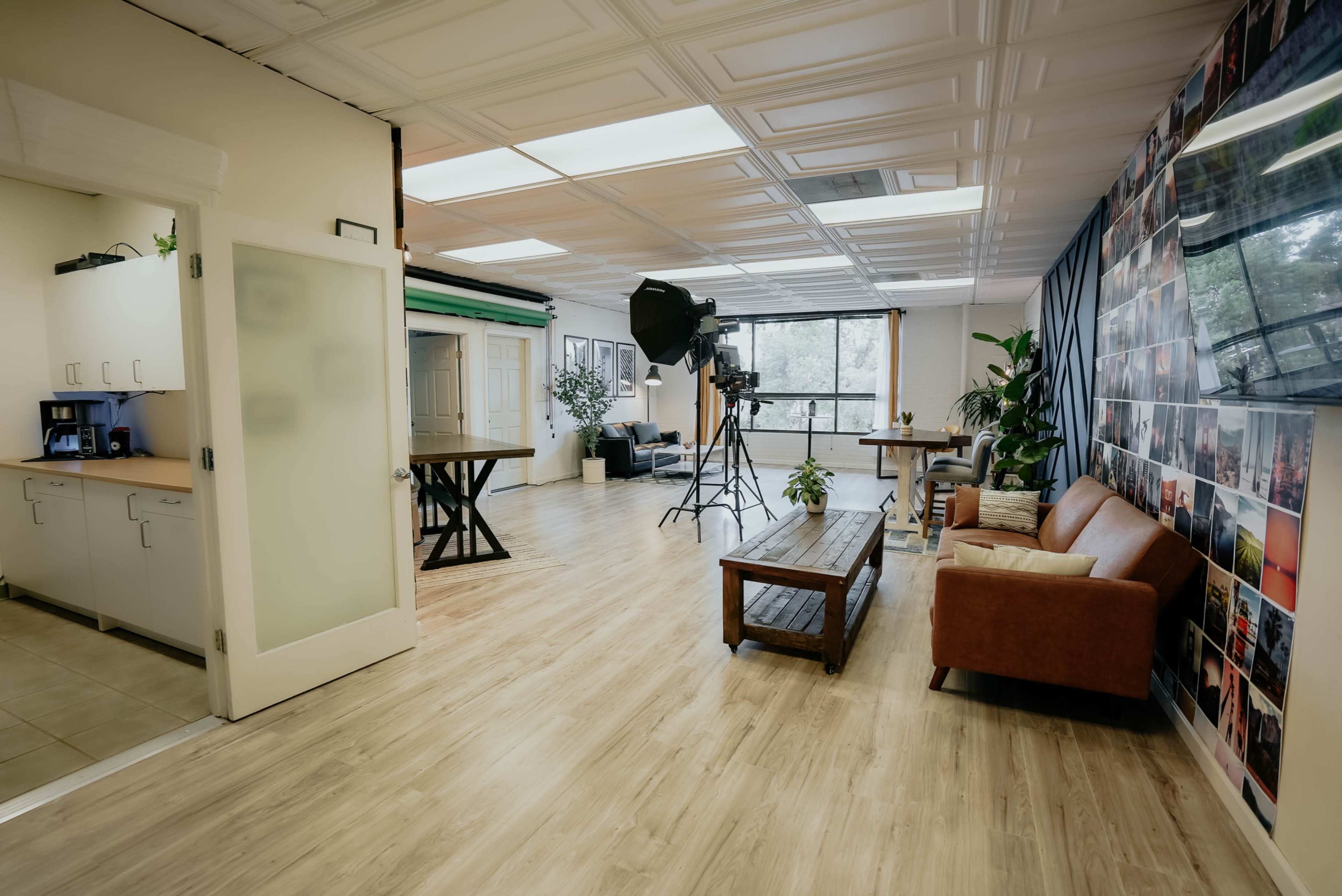 A modern studio space with a seating area, kitchenette, and backdrops for photography or filming.