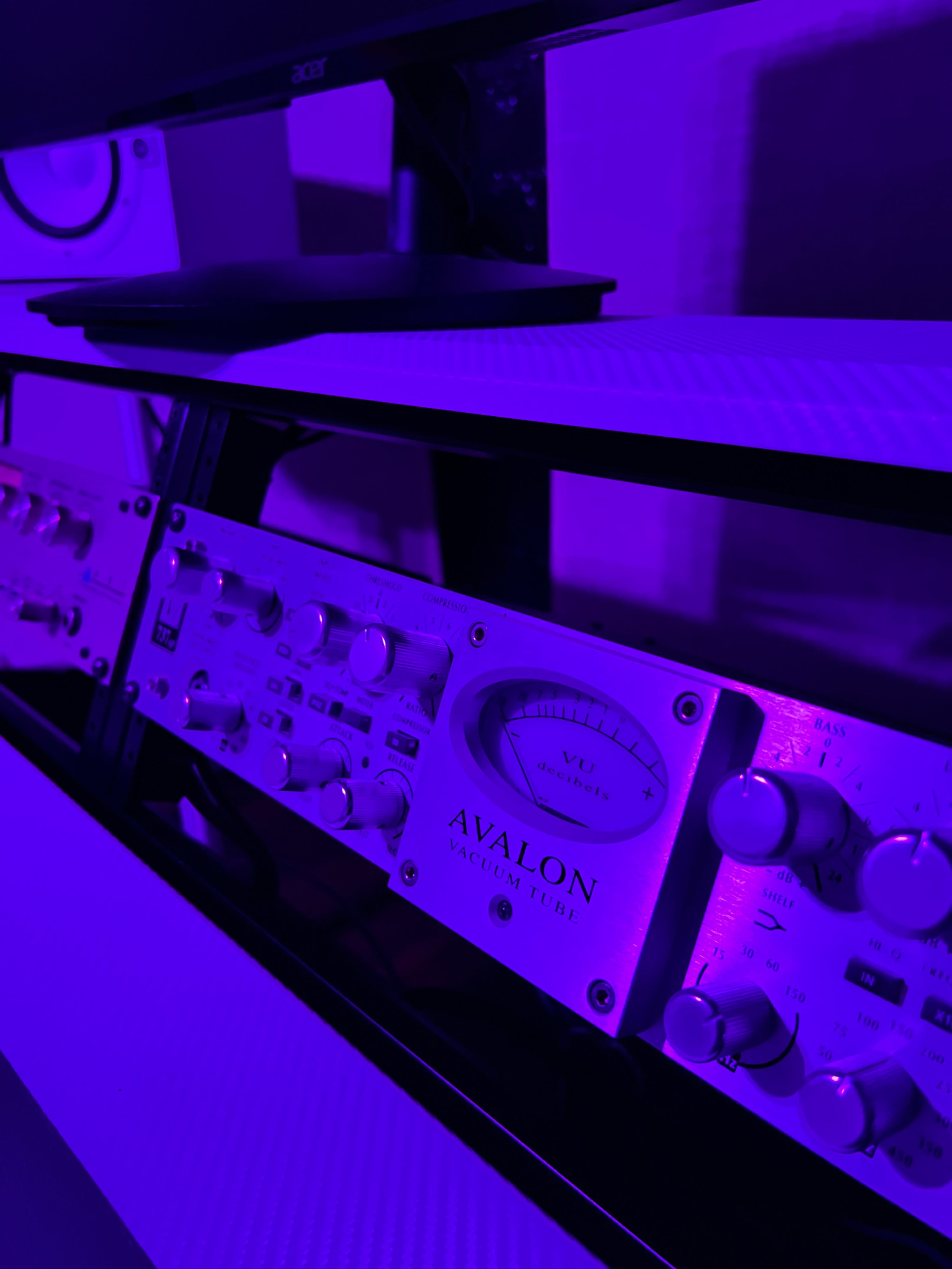 A close-up of an Avalon audio processor with purple lighting in a studio setting.