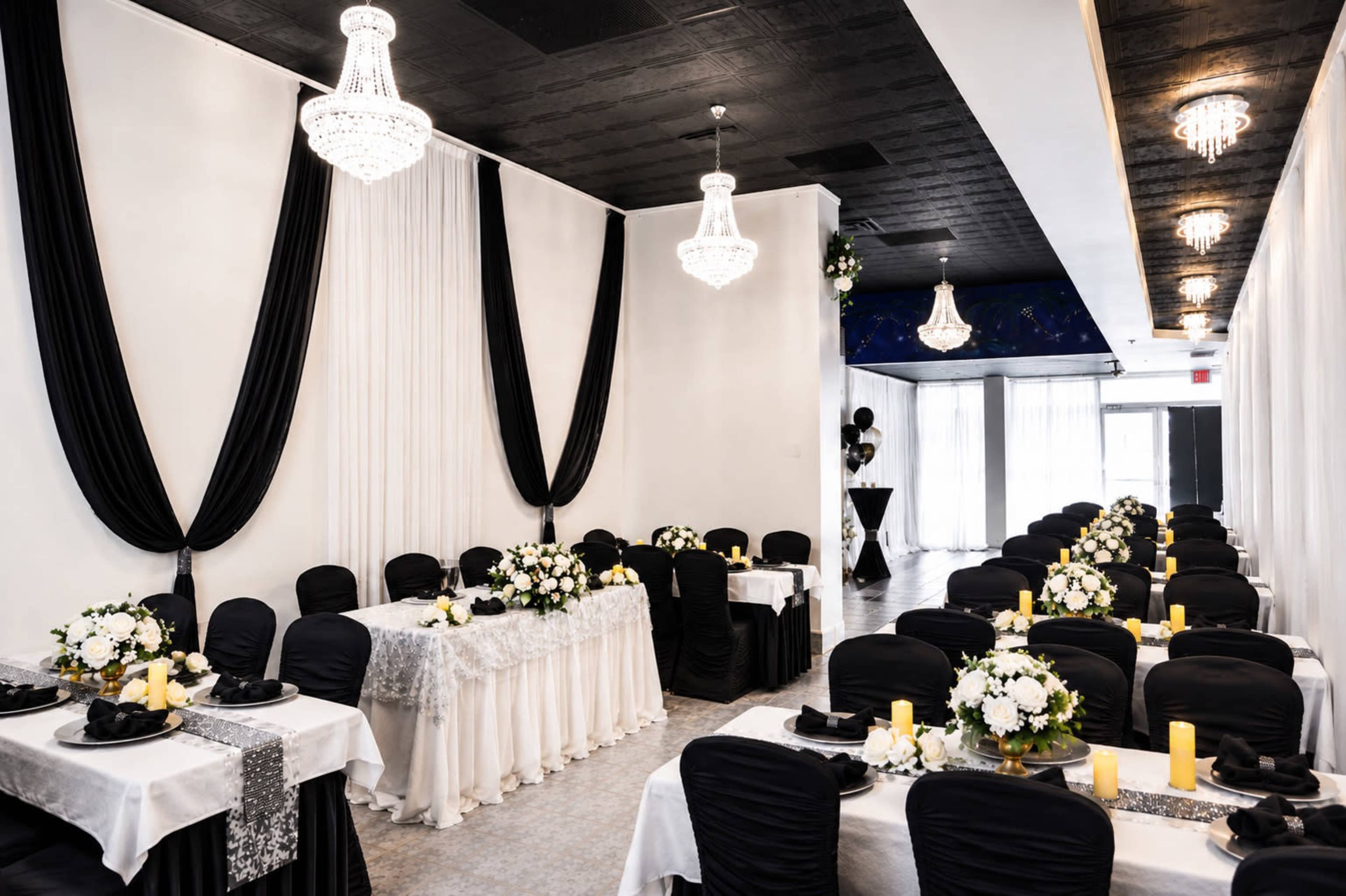 The image shows a banquet hall elegantly arranged with black and white table settings, featuring floral centerpieces and candle decorations.