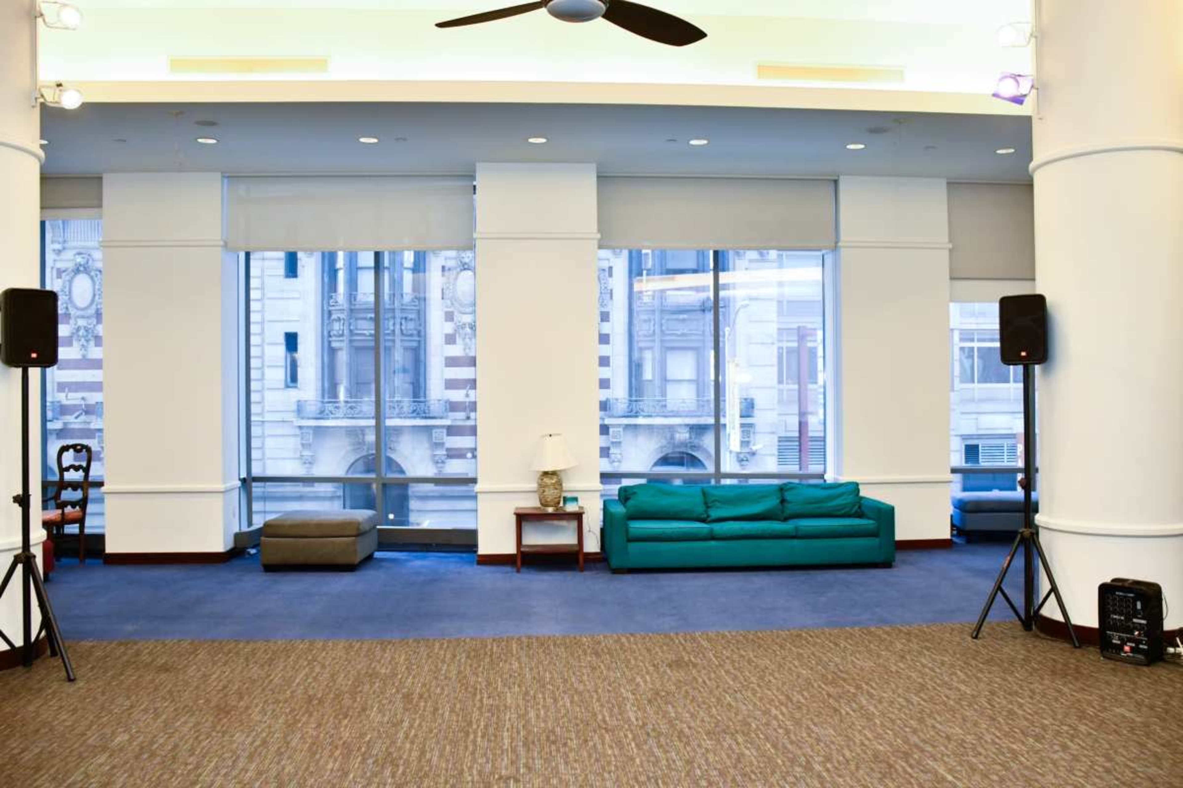 A spacious interior with a green couch, a small wooden table, and large windows displaying a cityscape outside.