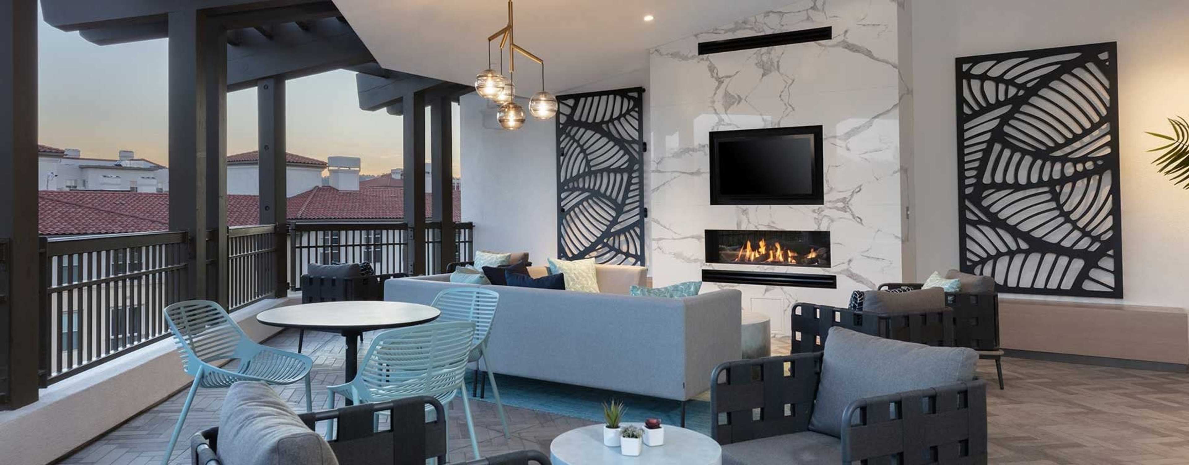 The image shows a modern, stylish lounge area with a fireplace, comfortable seating, and decorative wall designs.