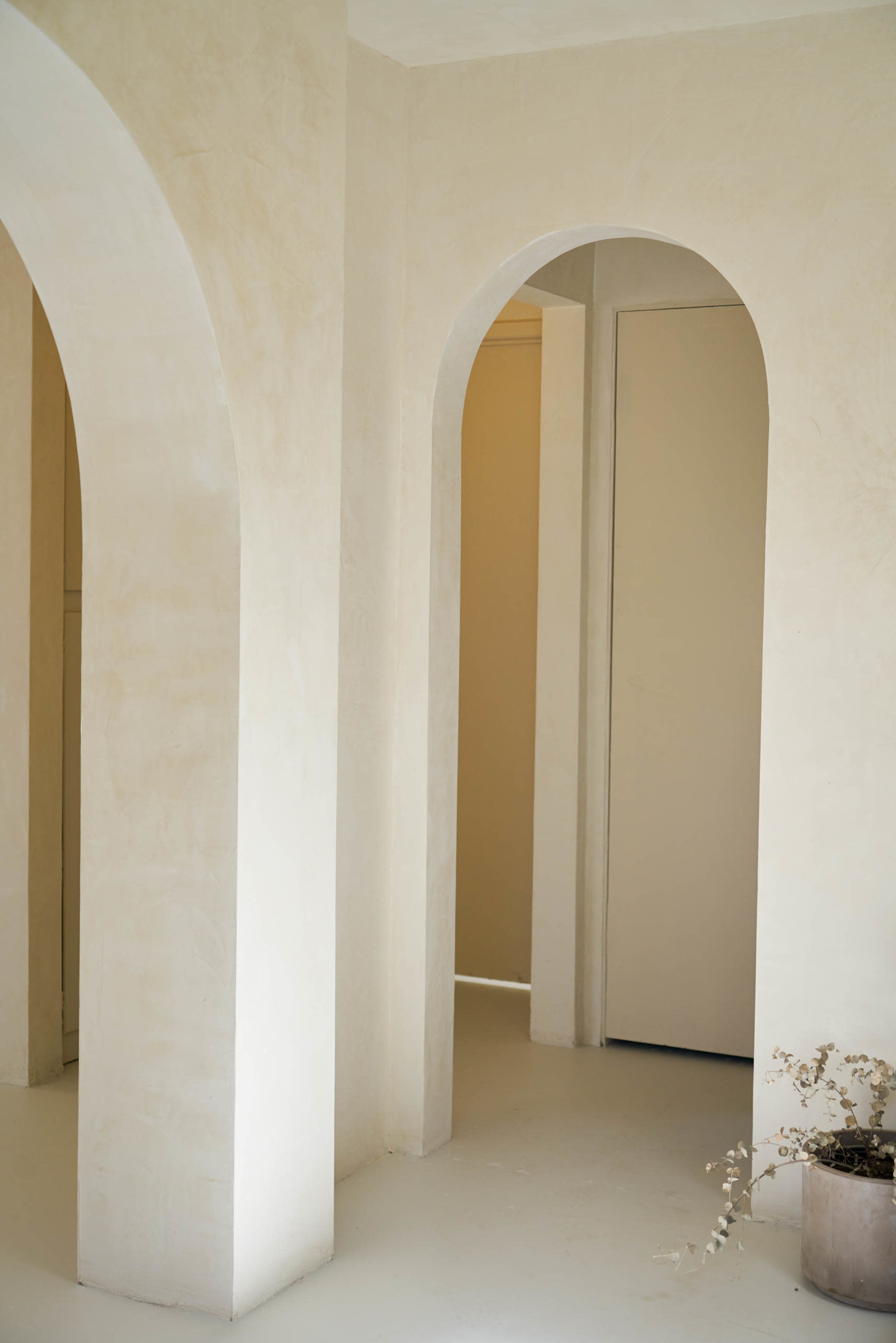 An interior space with light-colored walls and soft arches leading to doorways, creating an open and airy atmosphere.