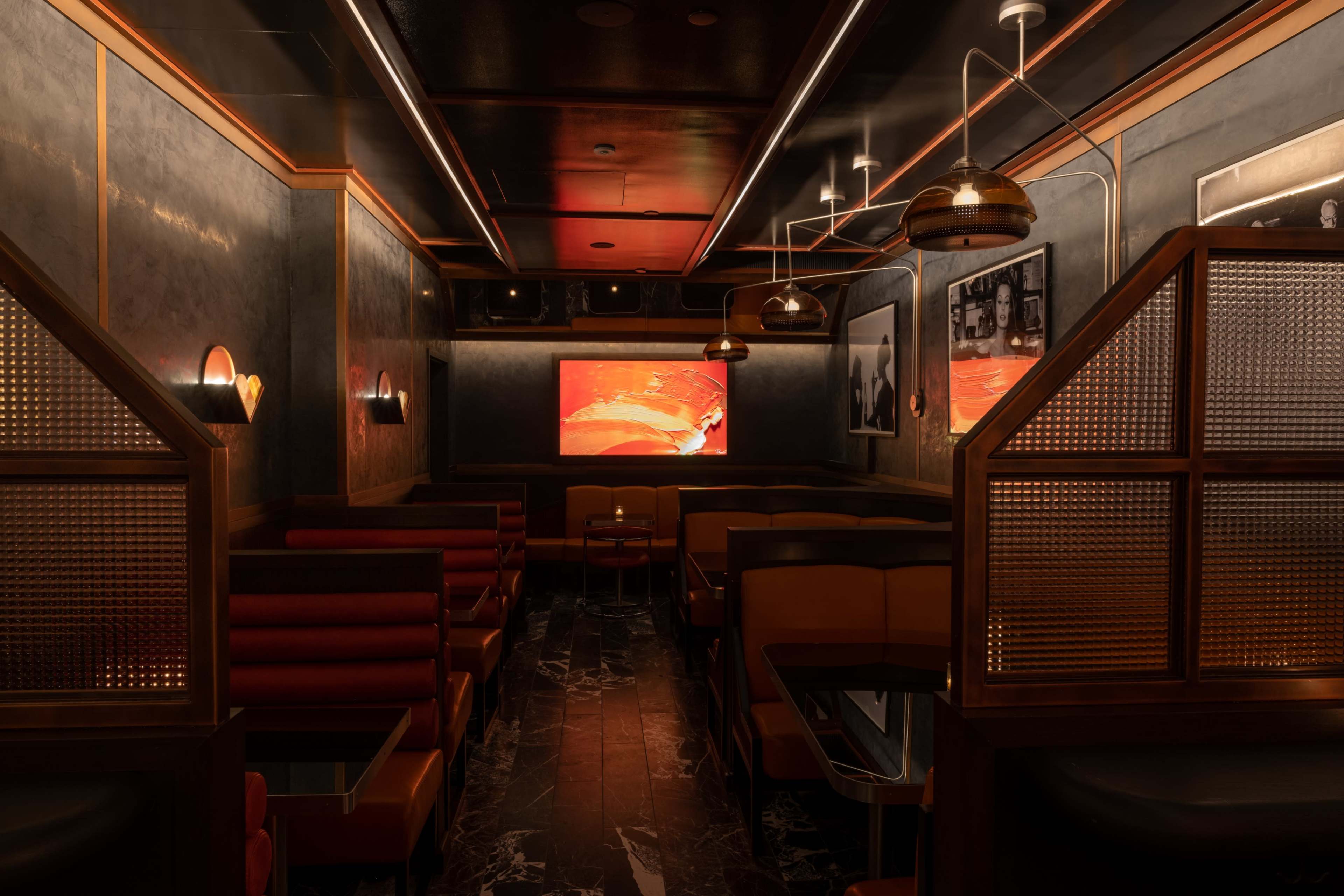 An elegantly designed restaurant interior featuring plush seating, dim lighting, and modern decor, including framed photographs on the walls.