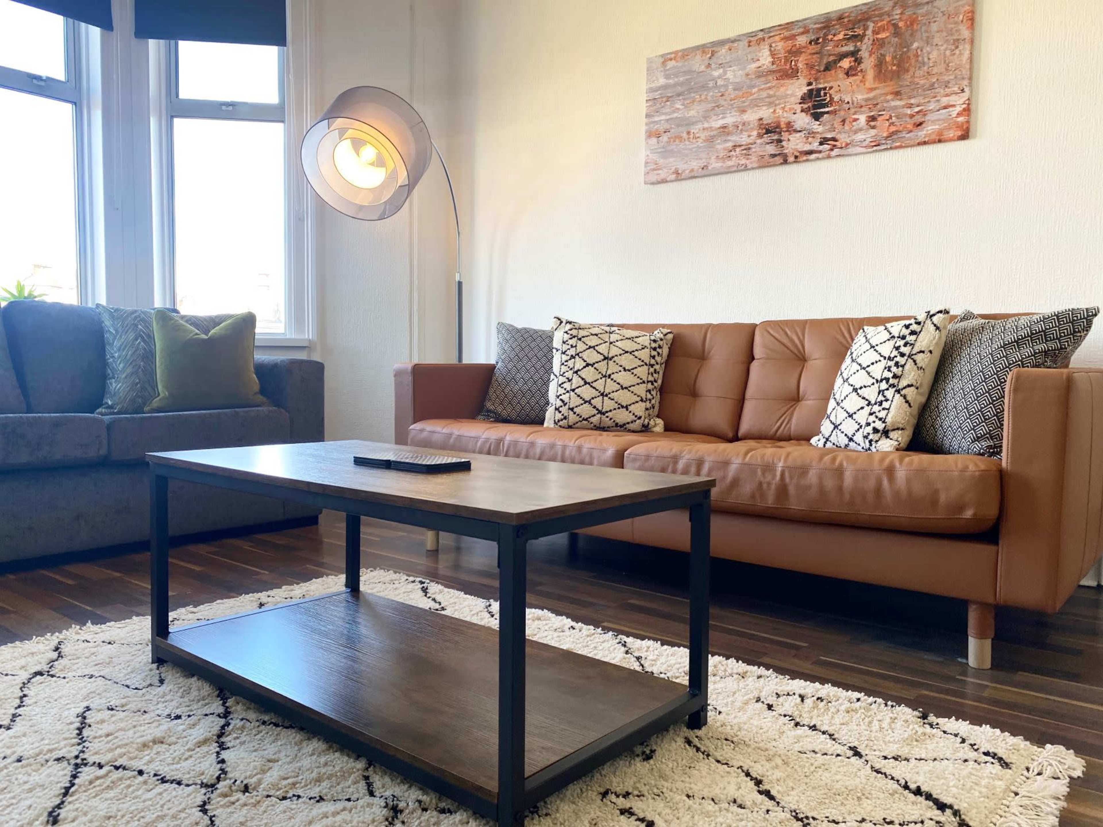 A living room with two sofas, a coffee table, and a rug on wooden flooring.